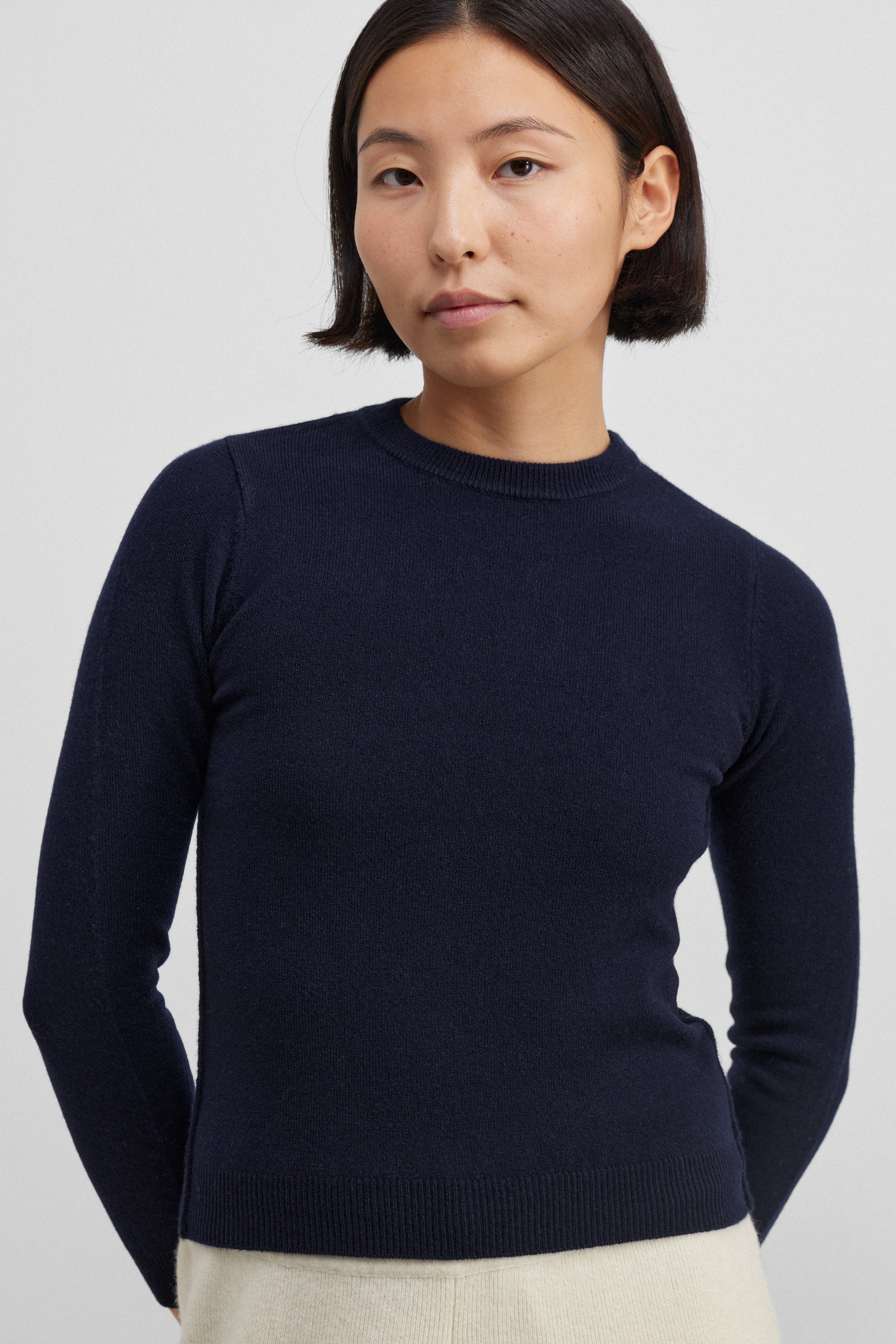woman wearing a navy blue slim-fit cashmere crewneck sweater with ribbed trims.