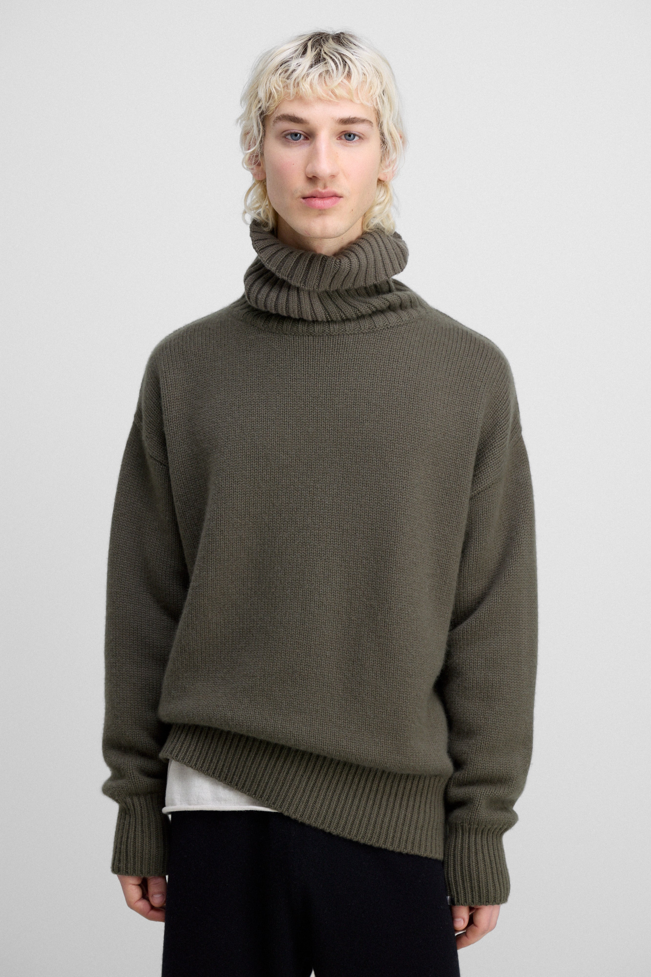 man wearing an army green heavy-knit cashmere turtleneck sweater with ribbed trims.