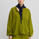 woman wearing a green relaxed-fit cashmere sweater with corozo buttons.