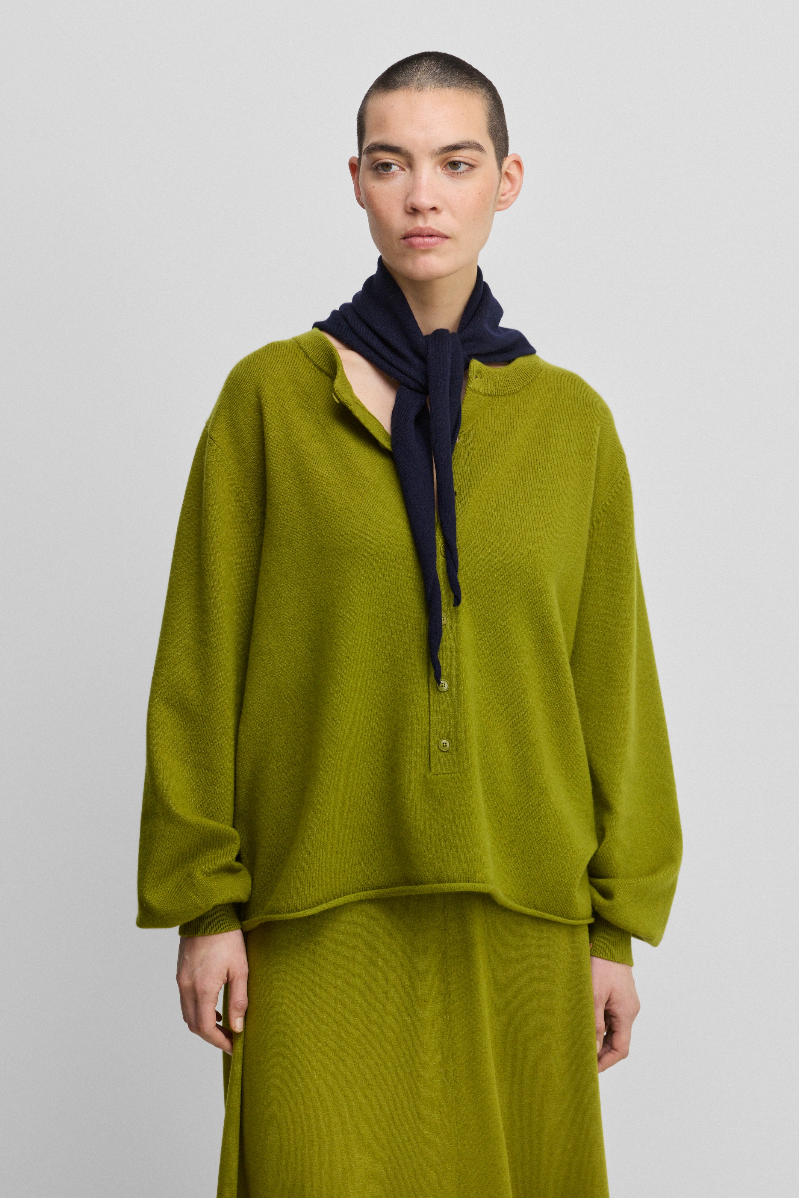 woman wearing a green relaxed-fit cashmere sweater with corozo buttons.