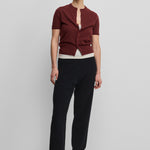 woman wearing black rib-knit cashmere pants with straight legs, styled with a burgundy cardigan.