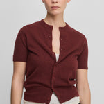 woman wearing a burgundy short-sleeved cashmere button-up cardigan with rib-knitted hem and cuffs.