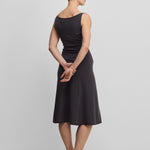 woman wearing a dark grey sleeveless wool cashmere a-line dress in midi length, shown from the back.