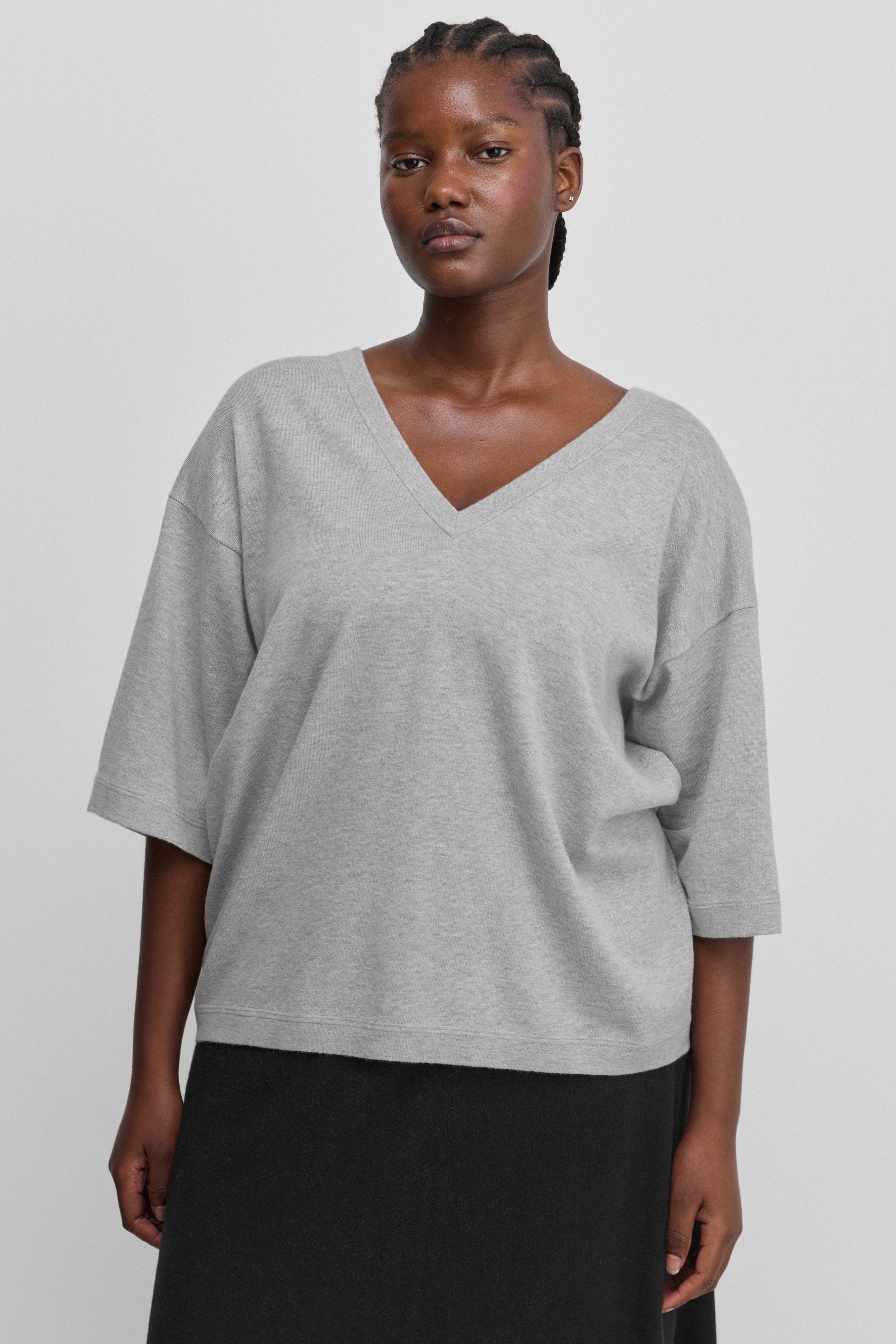 woman wearing an oversized grey cotton cashmere v-neck t-shirt with elbow-length sleeves.