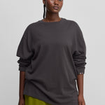 woman wearing a dark grey oversized long-sleeved cotton-cashmere t-shirt with a round neckline.