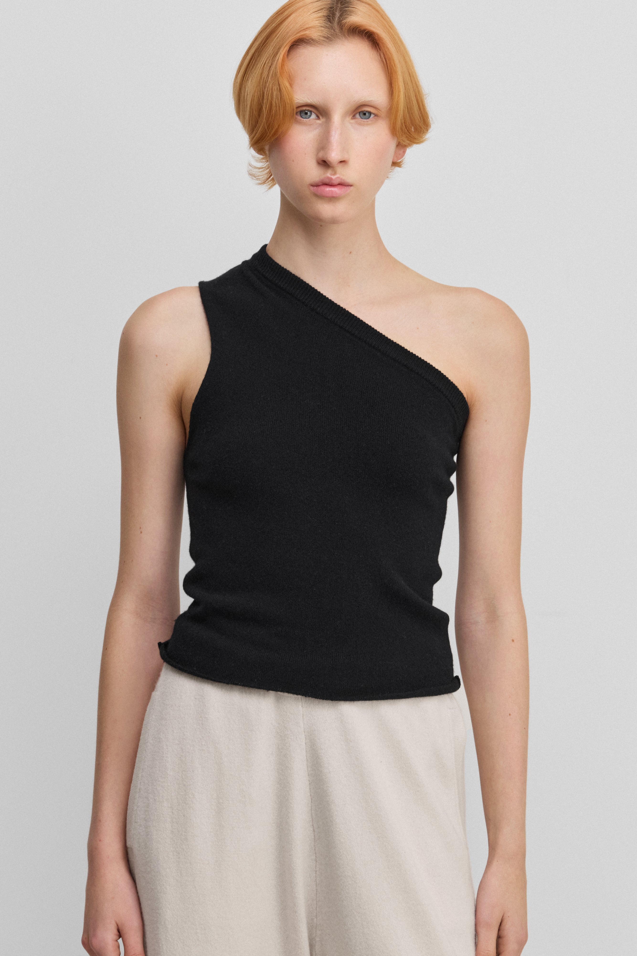 woman wearing a black fitted one-shoulder cashmere top.