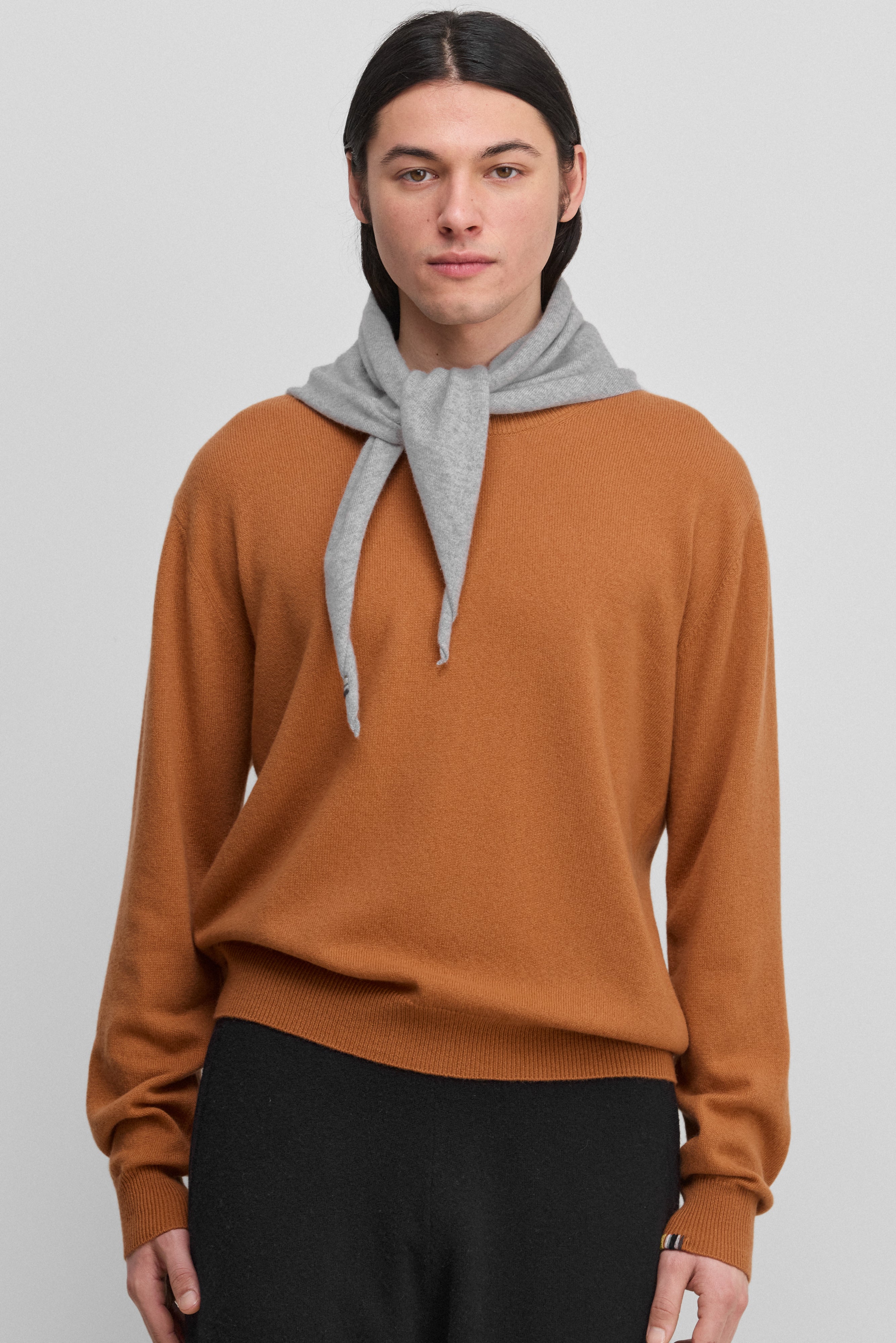 man wearing an orange cashmere crewneck sweater with ribbed hem, cuffs and neckline.