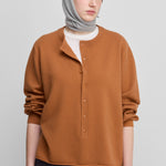 woman wearing an orange relaxed-fit cashmere sweater with corozo buttons.