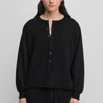 man wearing a black cashmere sweater with corozo buttons.