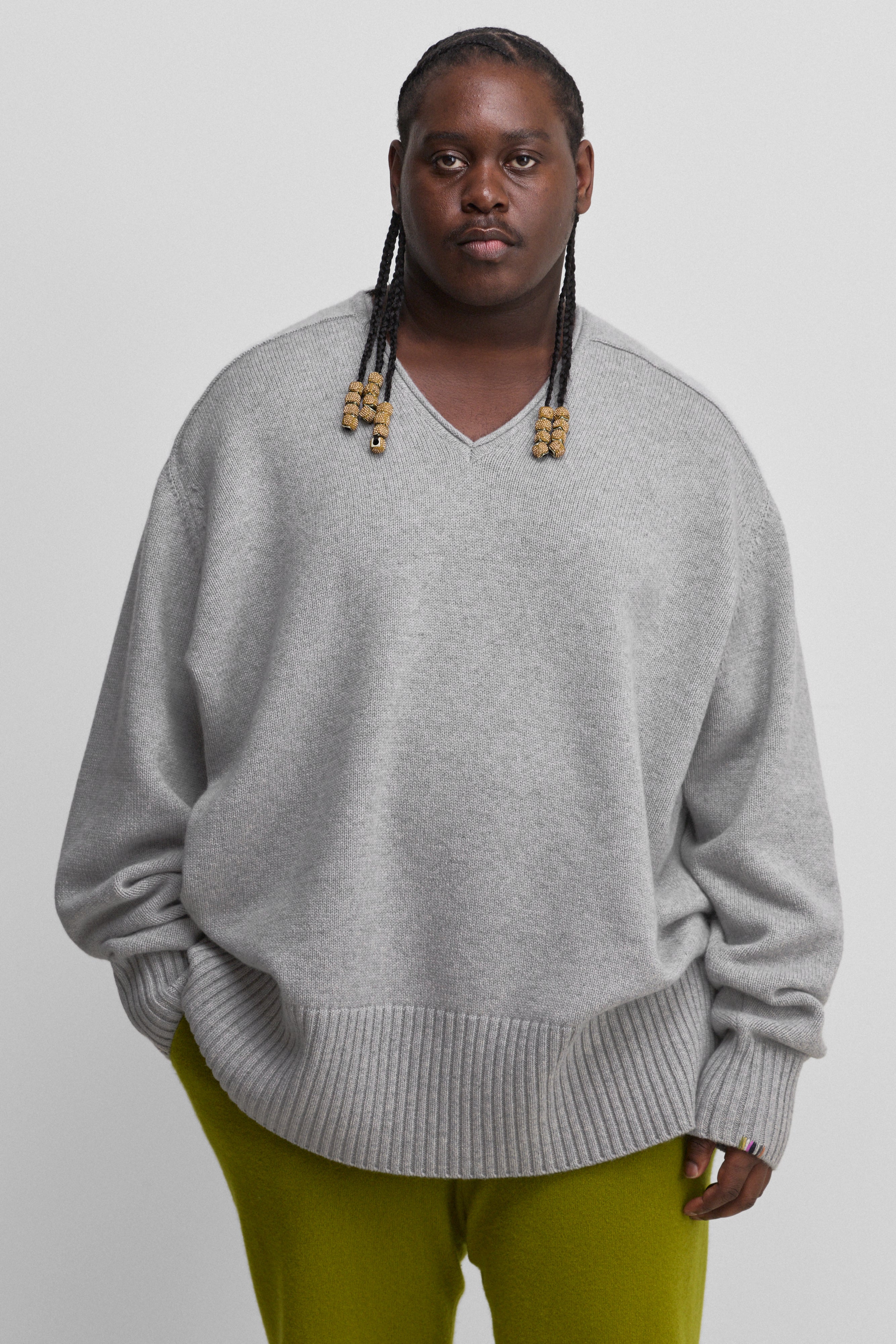 man wearing a grey oversized cashmere v-neck sweater with ribbed hem and cuffs.