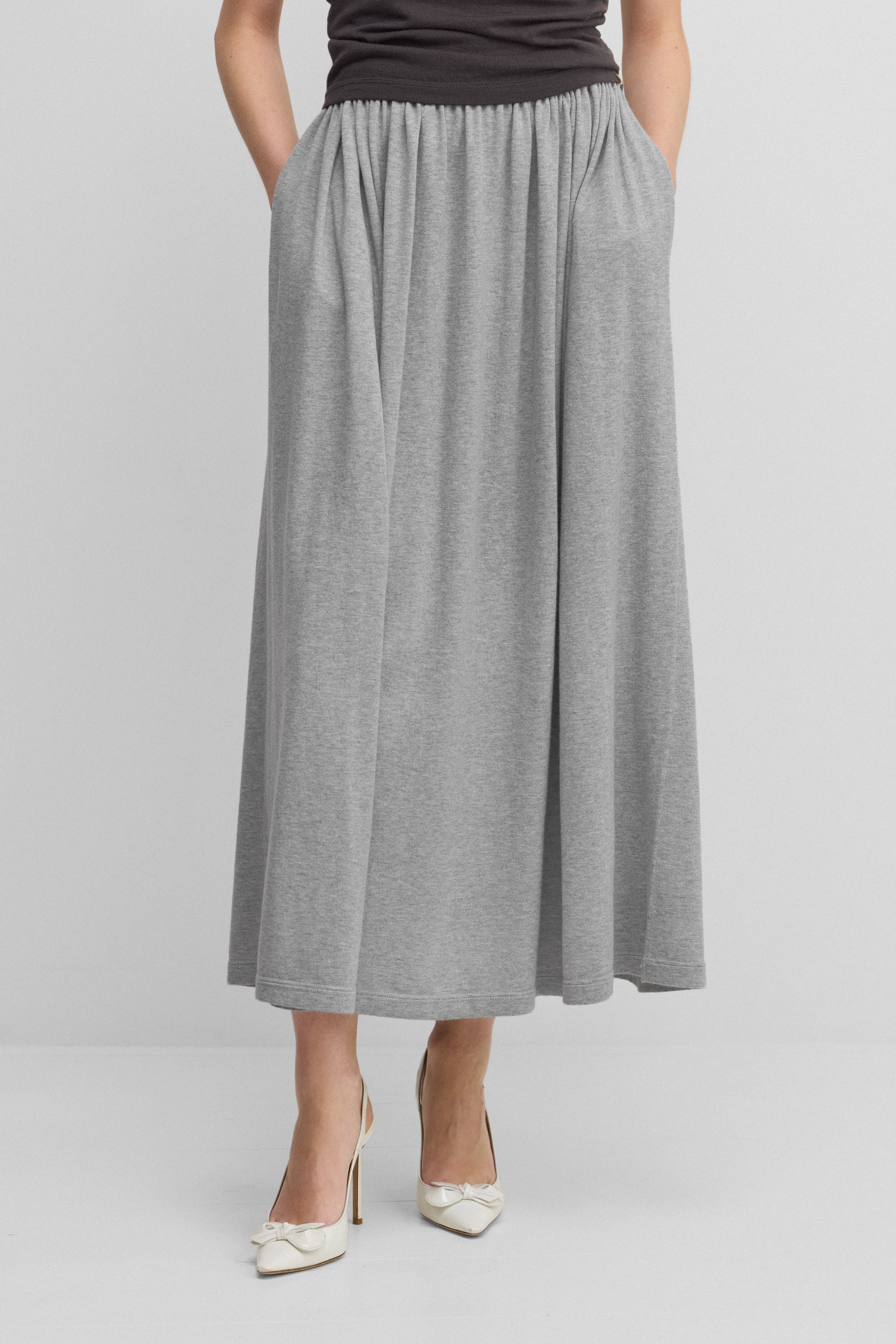 woman wearing a long grey cotton cashmere skirt with an elasticated waistband and two side pockets.