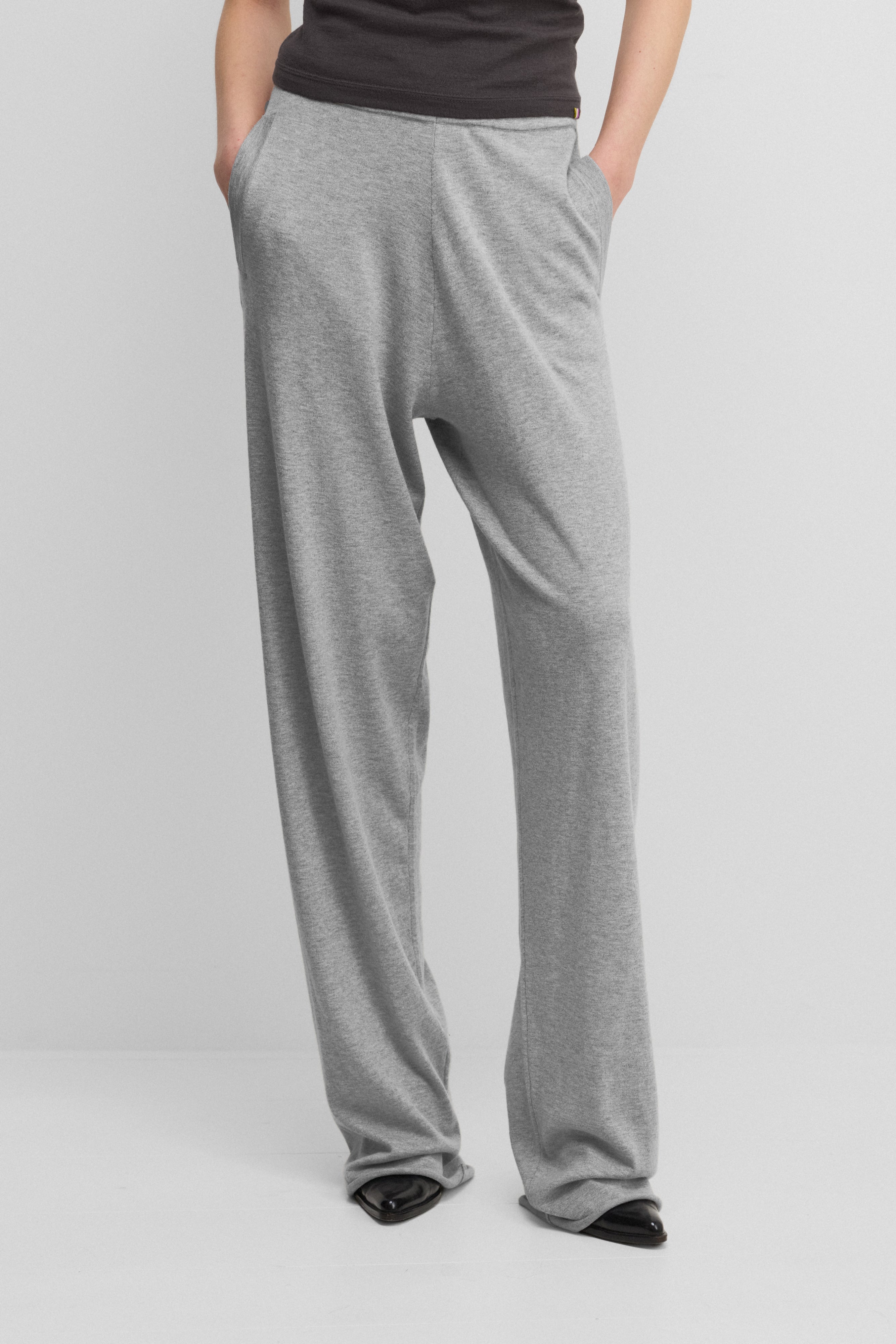 woman wearing loose-fit grey cotton cashmere pants with side pockets and drawstring waist.