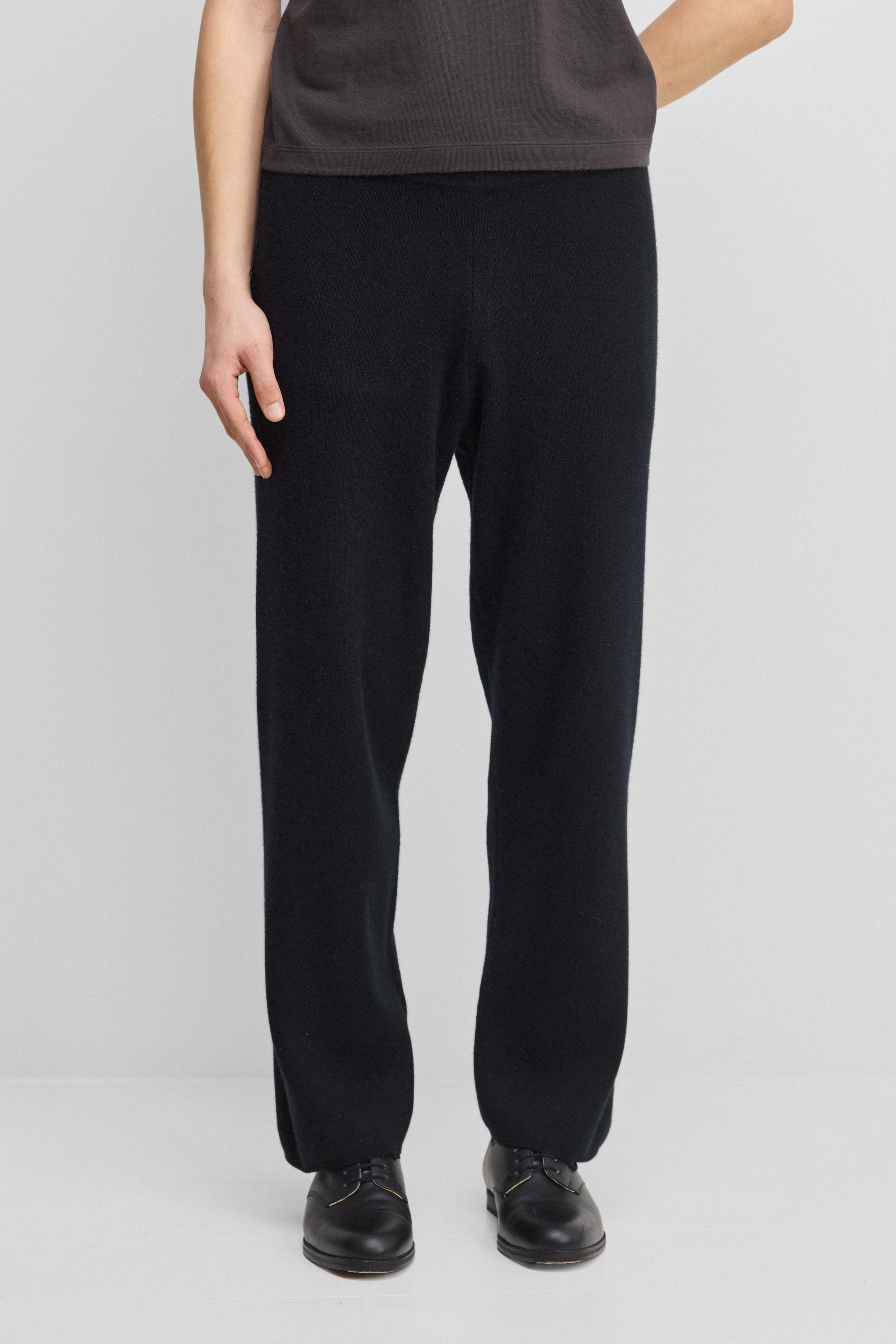 man wearing black rib-knit cashmere pants with a drawstring waistband and straight legs.