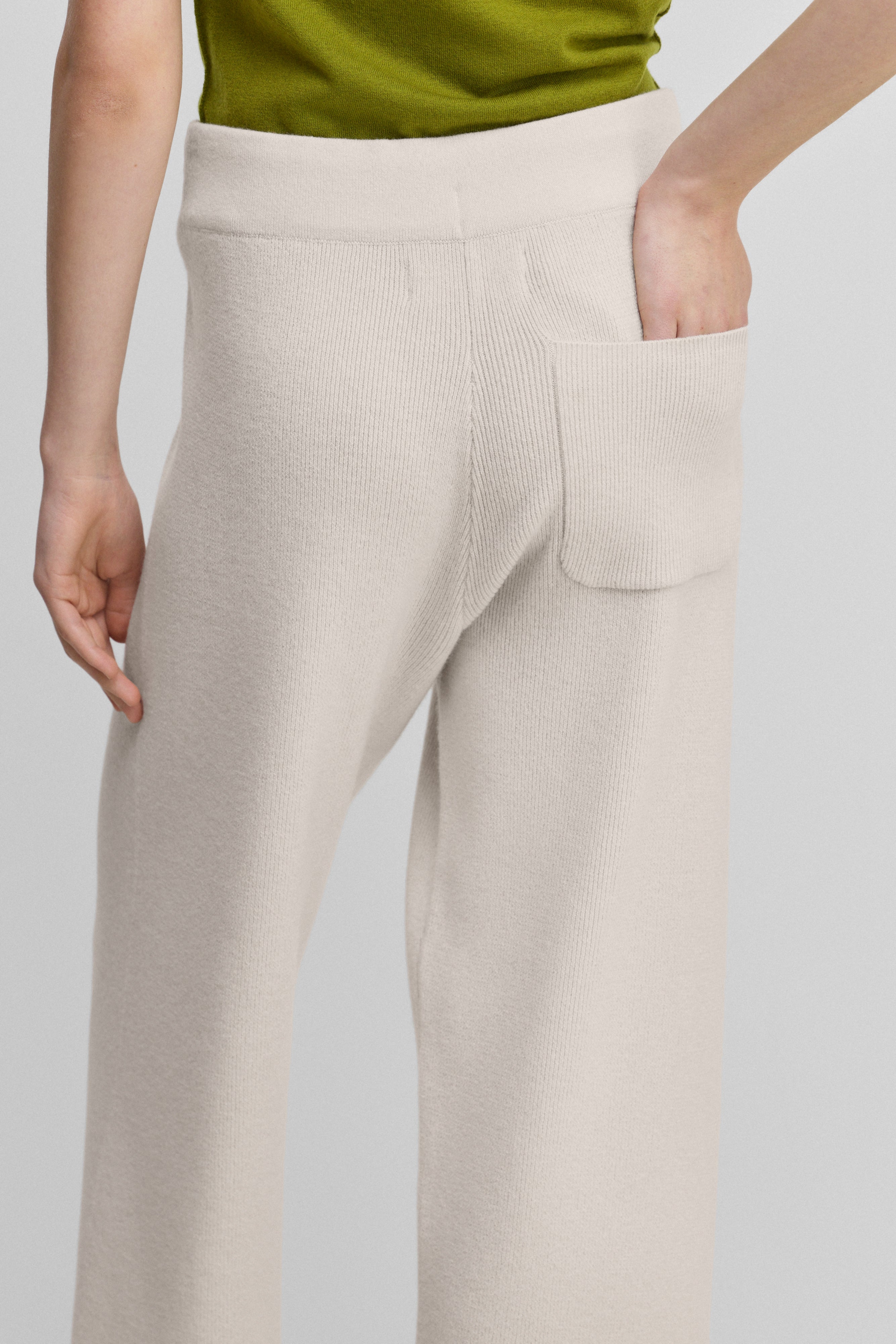 woman wearing white rib-knit cashmere pants with a drawstring waist and one back pocket, shown from the back.