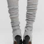 woman wearing light grey rib-knit cashmere leg warmers, styled with heels.