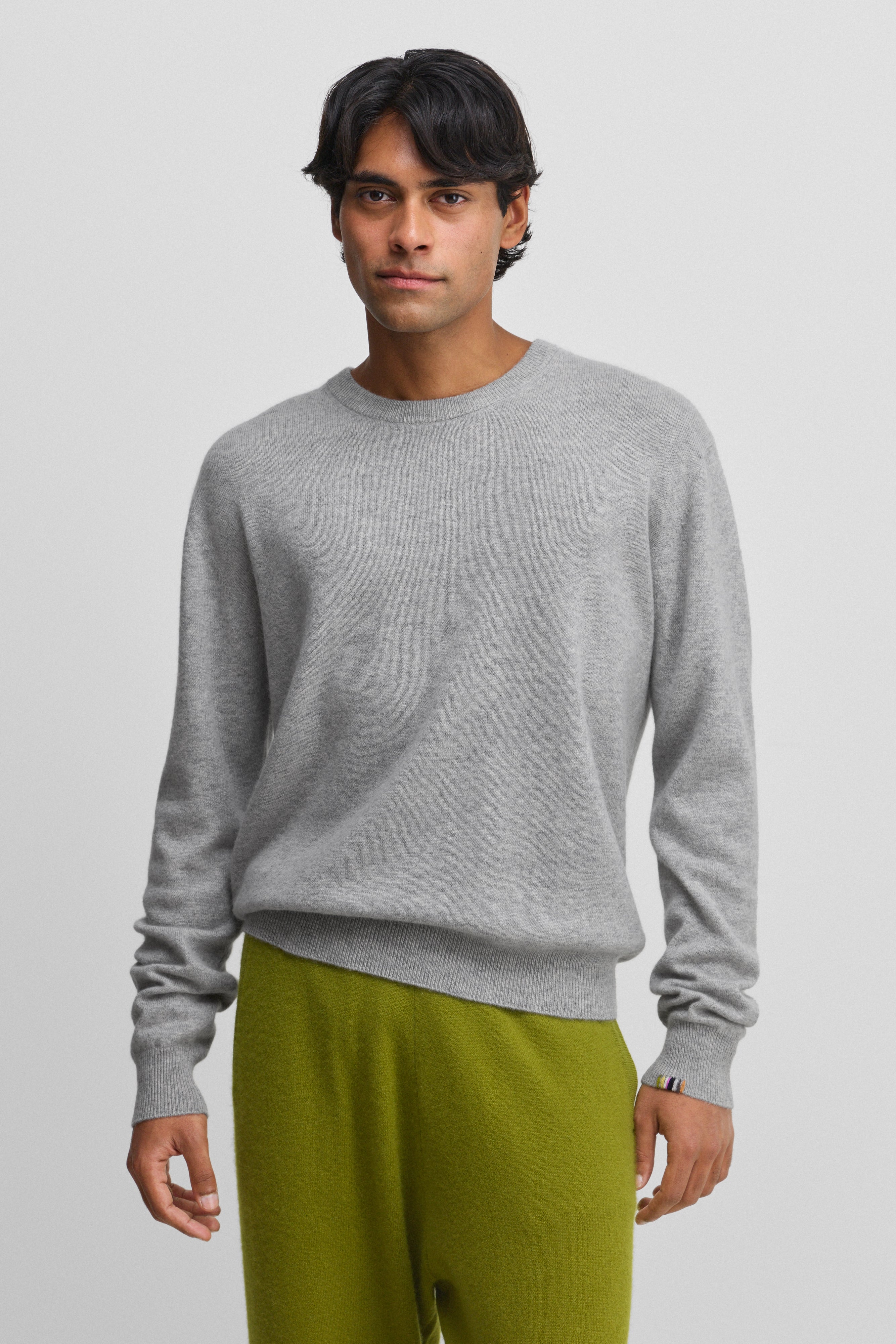 man wearing a grey cashmere crewneck sweater with ribbed hem, cuffs and neckline.
