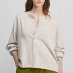 woman wearing a white relaxed-fit cashmere sweater with corozo buttons.