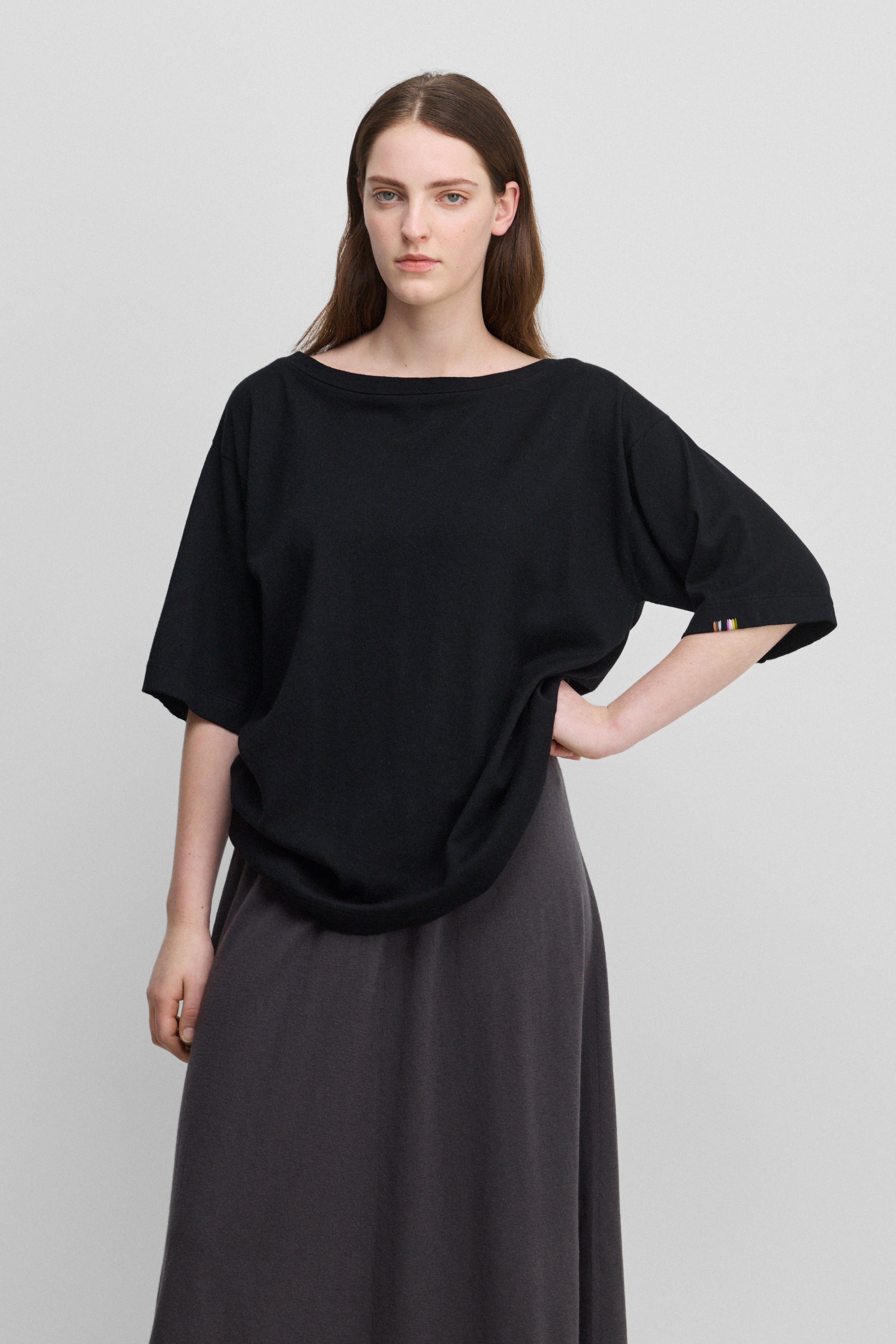 woman wearing an oversized black cotton cashmere t-shirt with a boat neck and elbow-length sleeves.