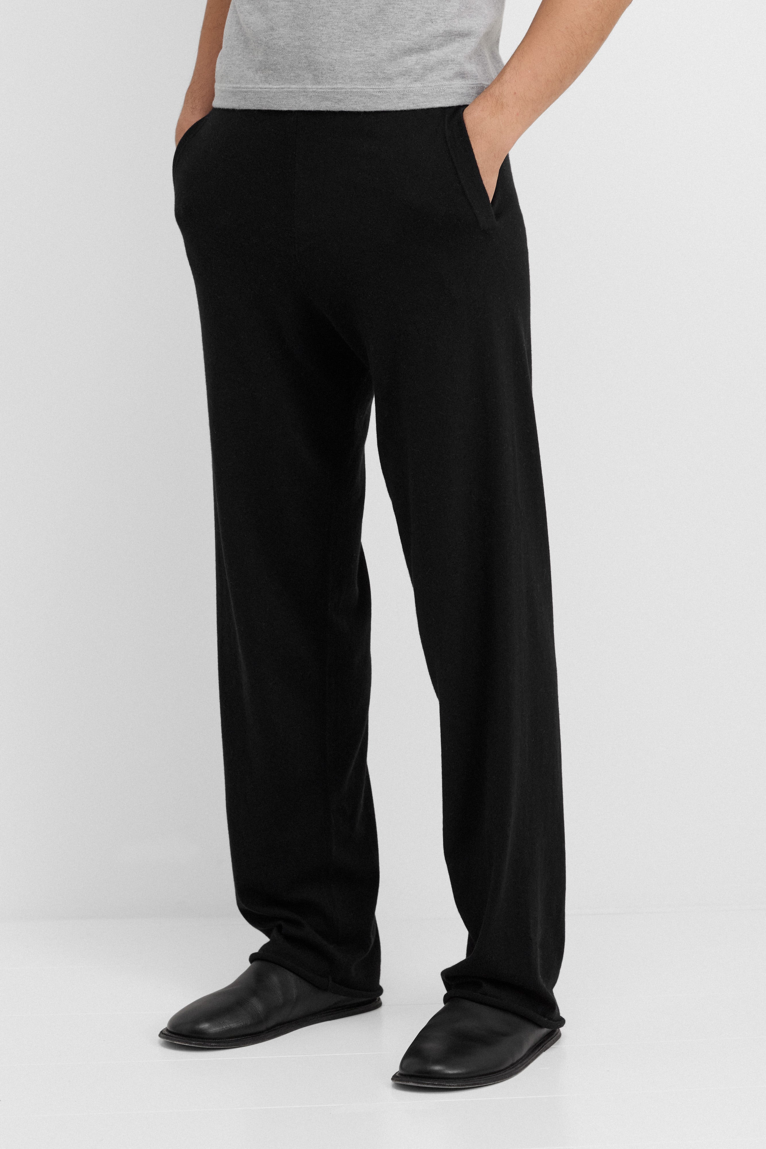 man wearing loose-fit black cotton cashmere pants with side pockets and drawstring waist.