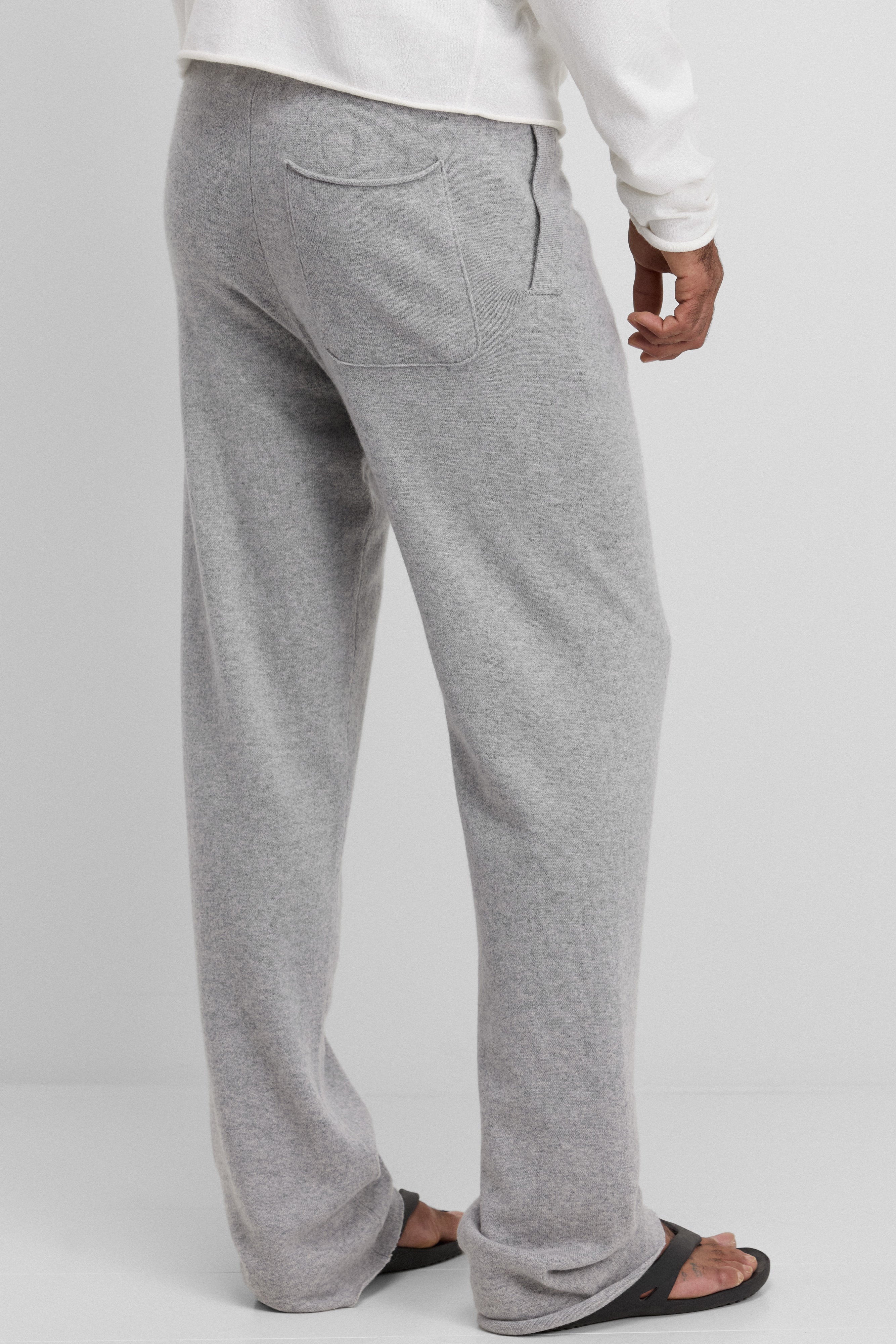 man wearing light grey cashmere pants with straight legs, side pockets and a back pocket, shown from the back.