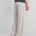 man wearing white rib-knit cashmere pants with straight legs and one back pocket, shown from the back.