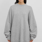 woman wearing an oversized grey cashmere crewneck sweater with long sleeves and ribbed trims.