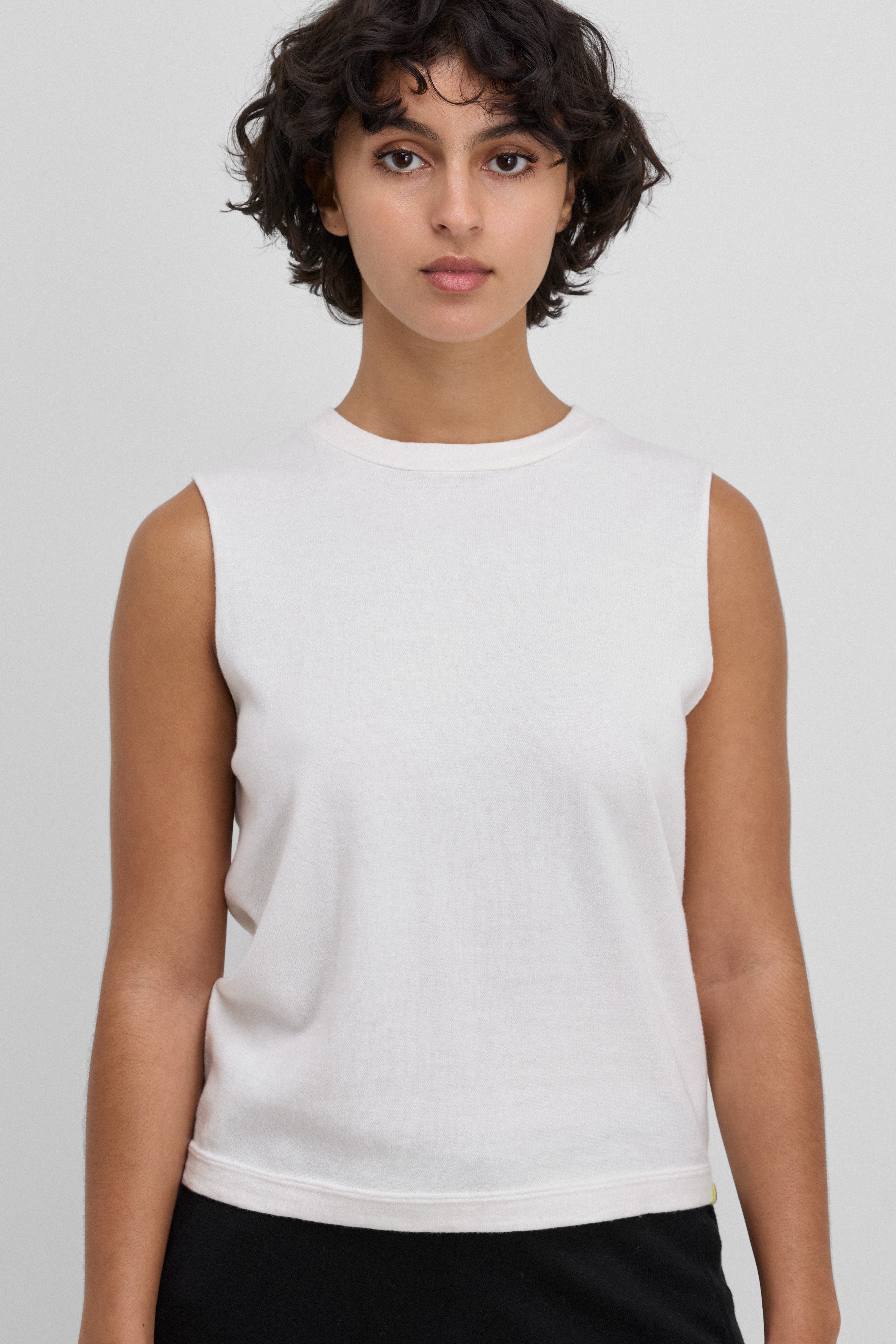 woman wearing a fitted white sleeveless crew-neck top in cotton cashmere.