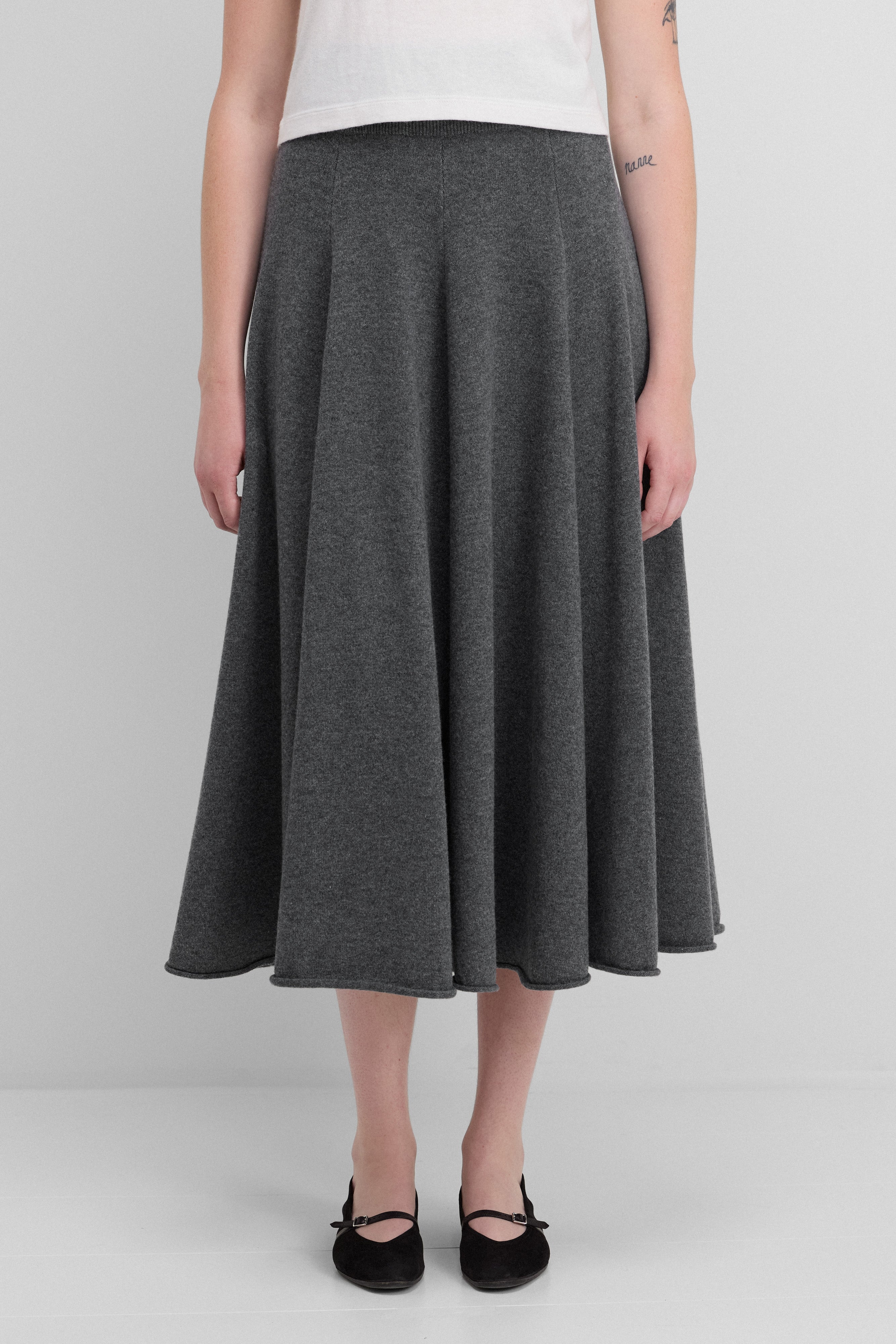 woman wearing a dark grey flared cashmere midi skirt with ribbed waistband.