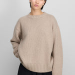 woman wearing a loose-fit beige cashmere crew-neck sweater with ribbed trims.