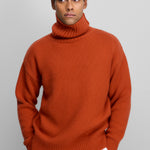 man wearing a dark orange heavy-knit cashmere turtleneck sweater with ribbed trims.