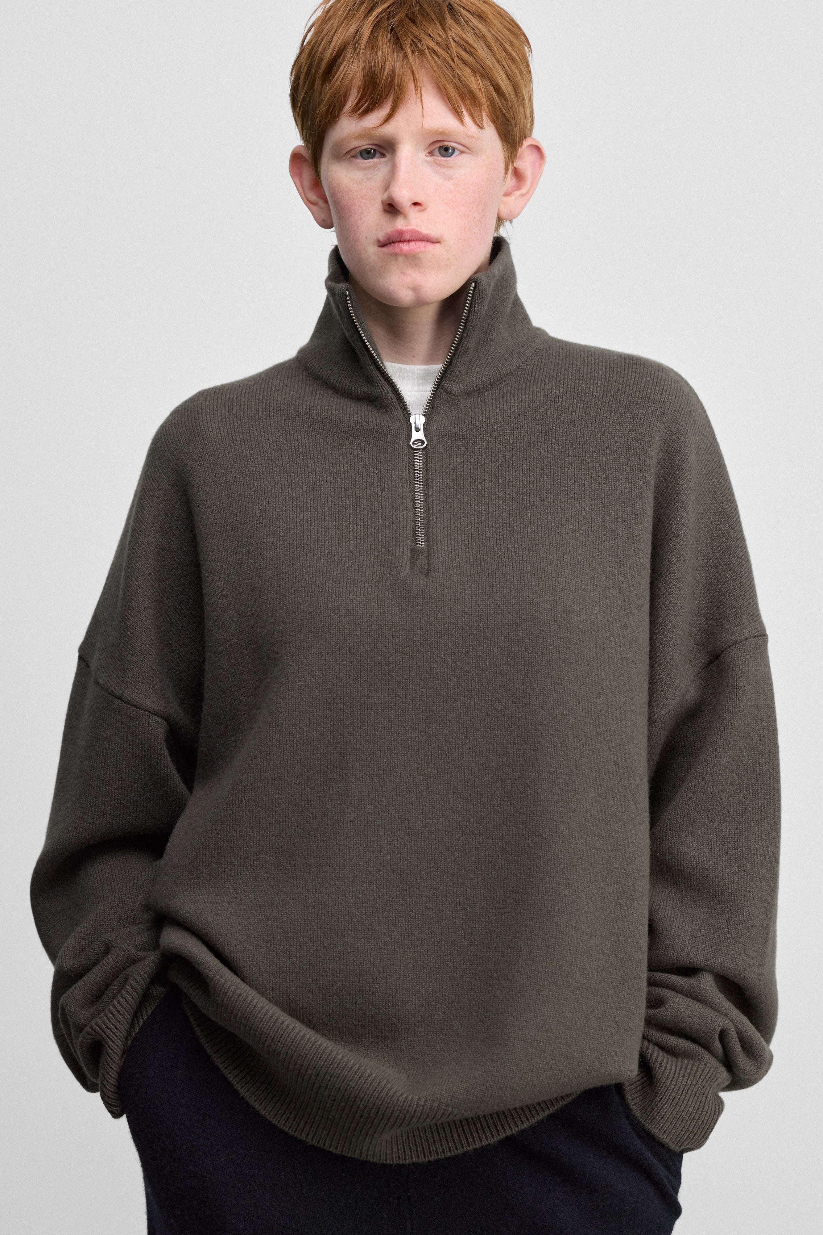 woman wearing a loose-fit army green quarter-zip cashmere sweater with drop shoulder and ribbed trims.