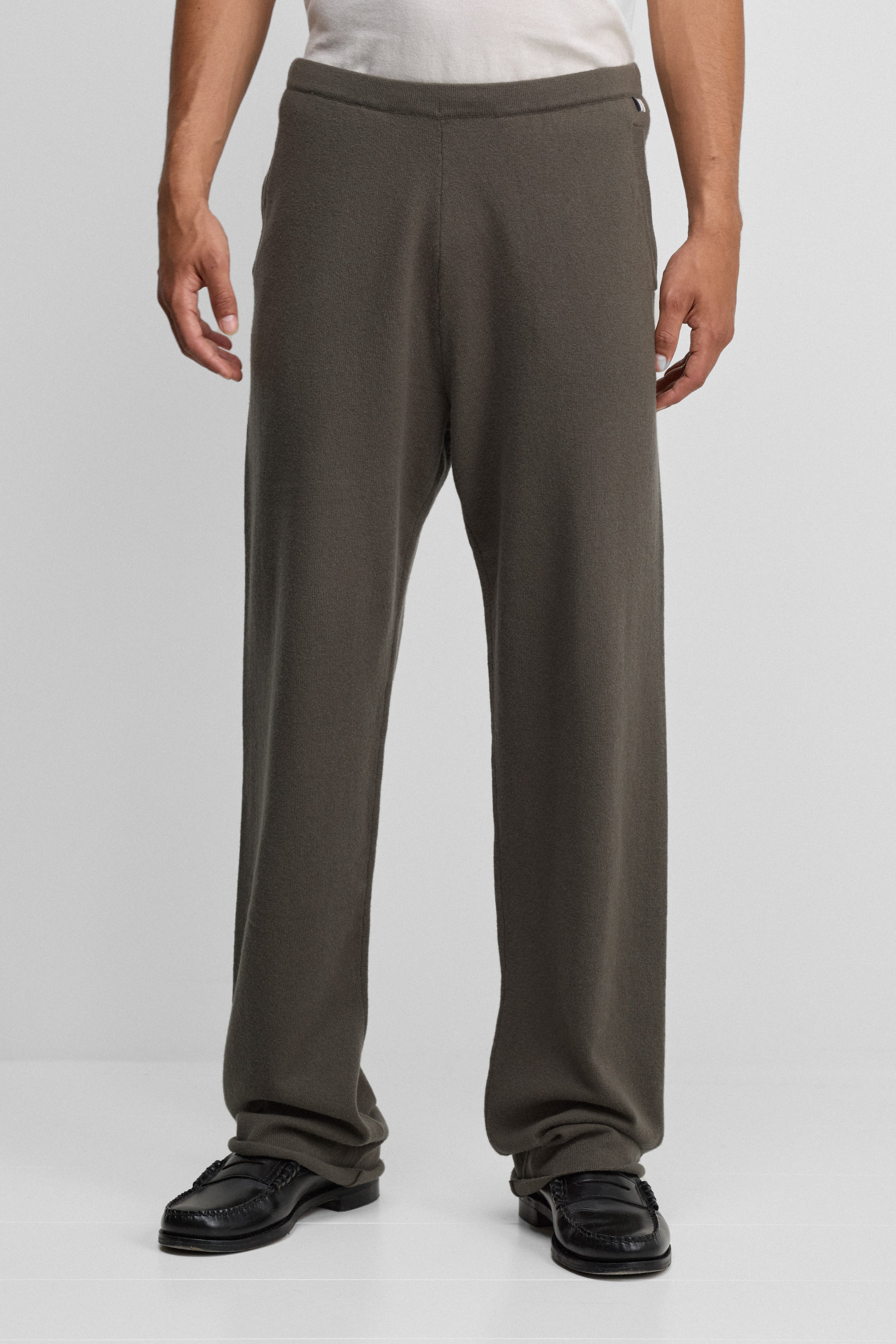 man wearing army green cashmere pants with straight legs, side pockets and a drawstring waist.