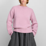 woman wearing a loose-fit pink cashmere crew-neck sweater with ribbed trims.