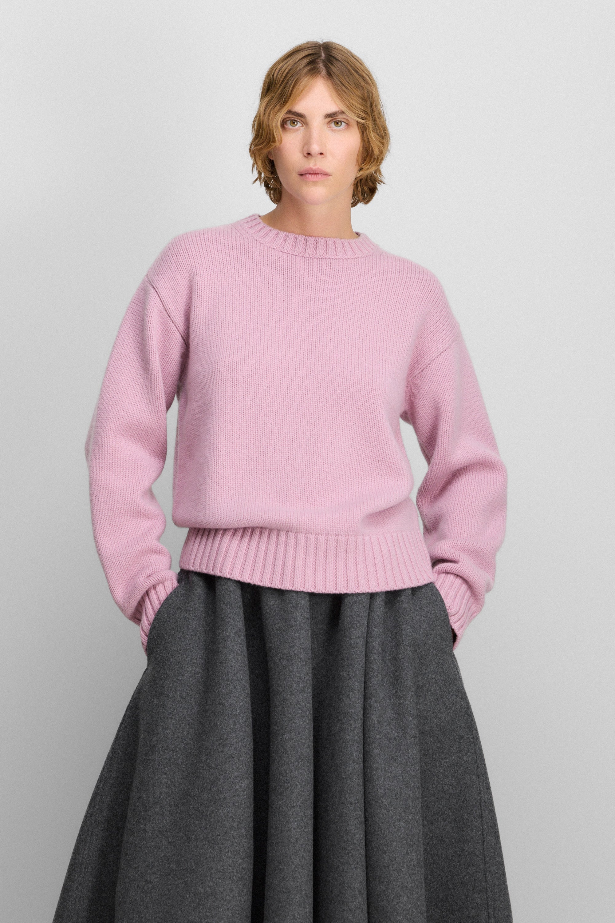 woman wearing a loose-fit pink cashmere crew-neck sweater with ribbed trims.