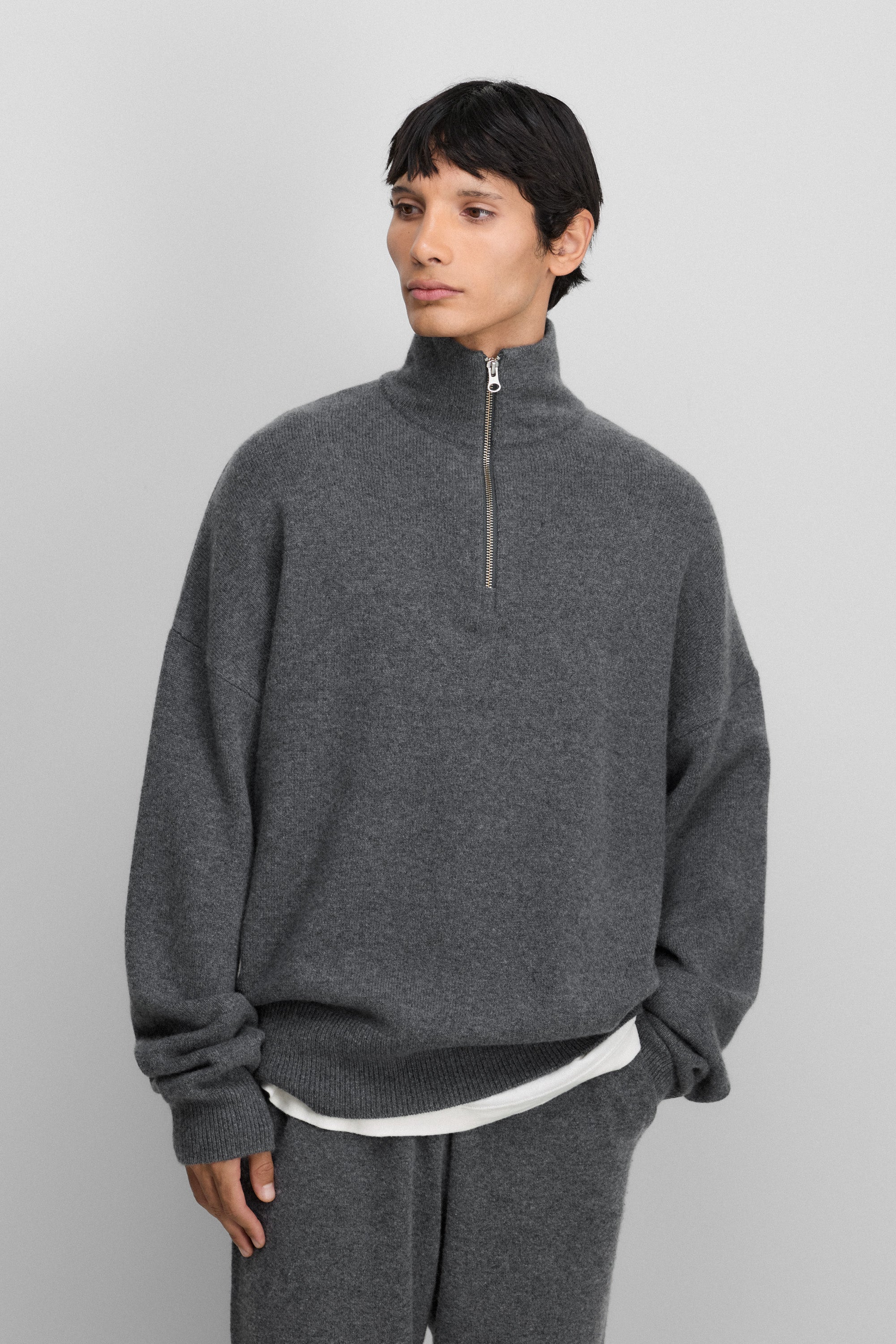 man wearing a dark grey quarter-zip cashmere sweater with drop shoulder and ribbed trims.