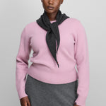 woman wearing a pink cashmere crew-neck sweater with rib-knitted hem and cuffs, styled with a grey scarf.