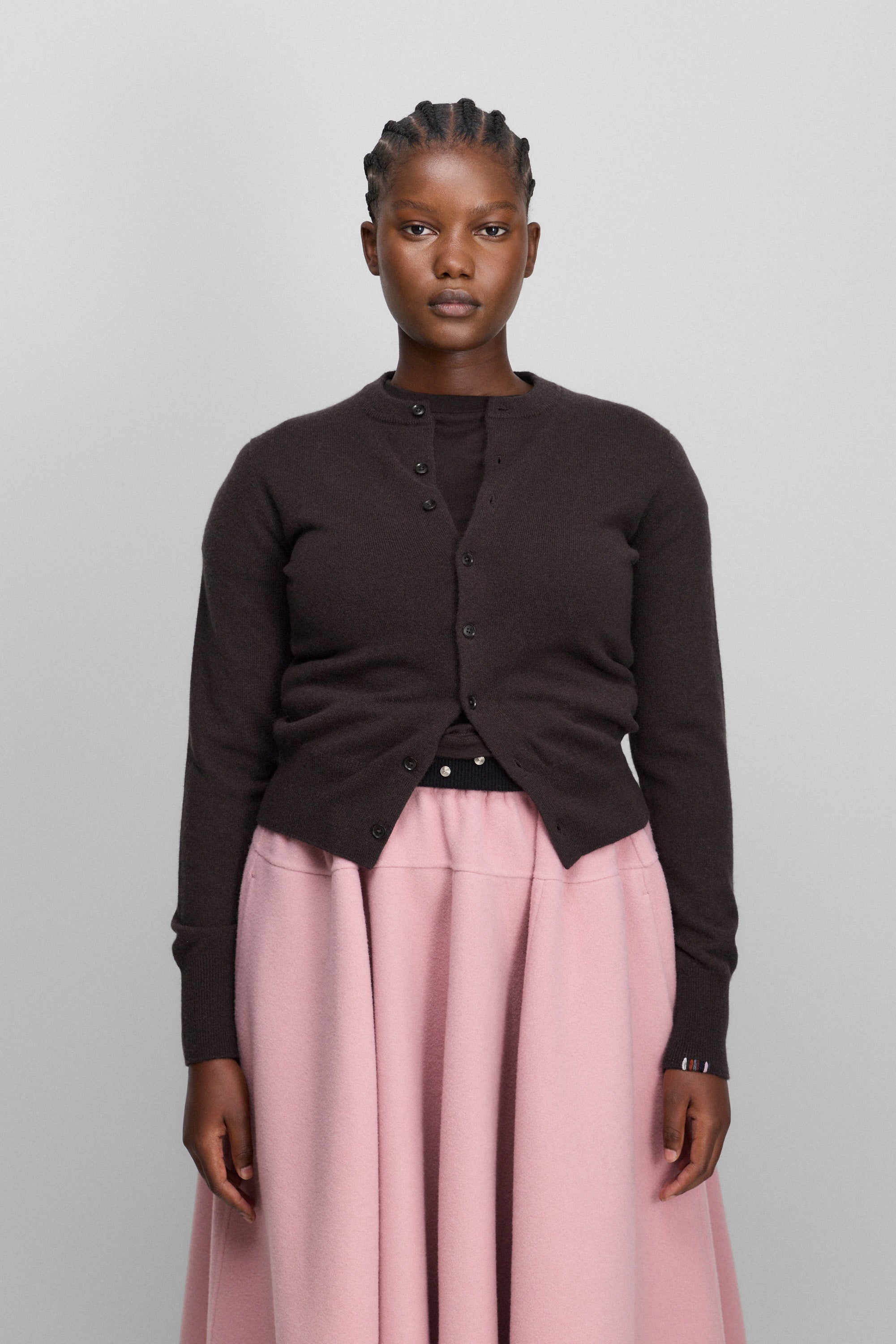woman wearing a dark brown cashmere crew-neck cardigan with eight corozo buttons and ribbed trims.
