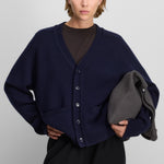 woman wearing a navy blue heavy-knit cashmere v-neck cardigan with five corozo buttons and ribbed trims.
