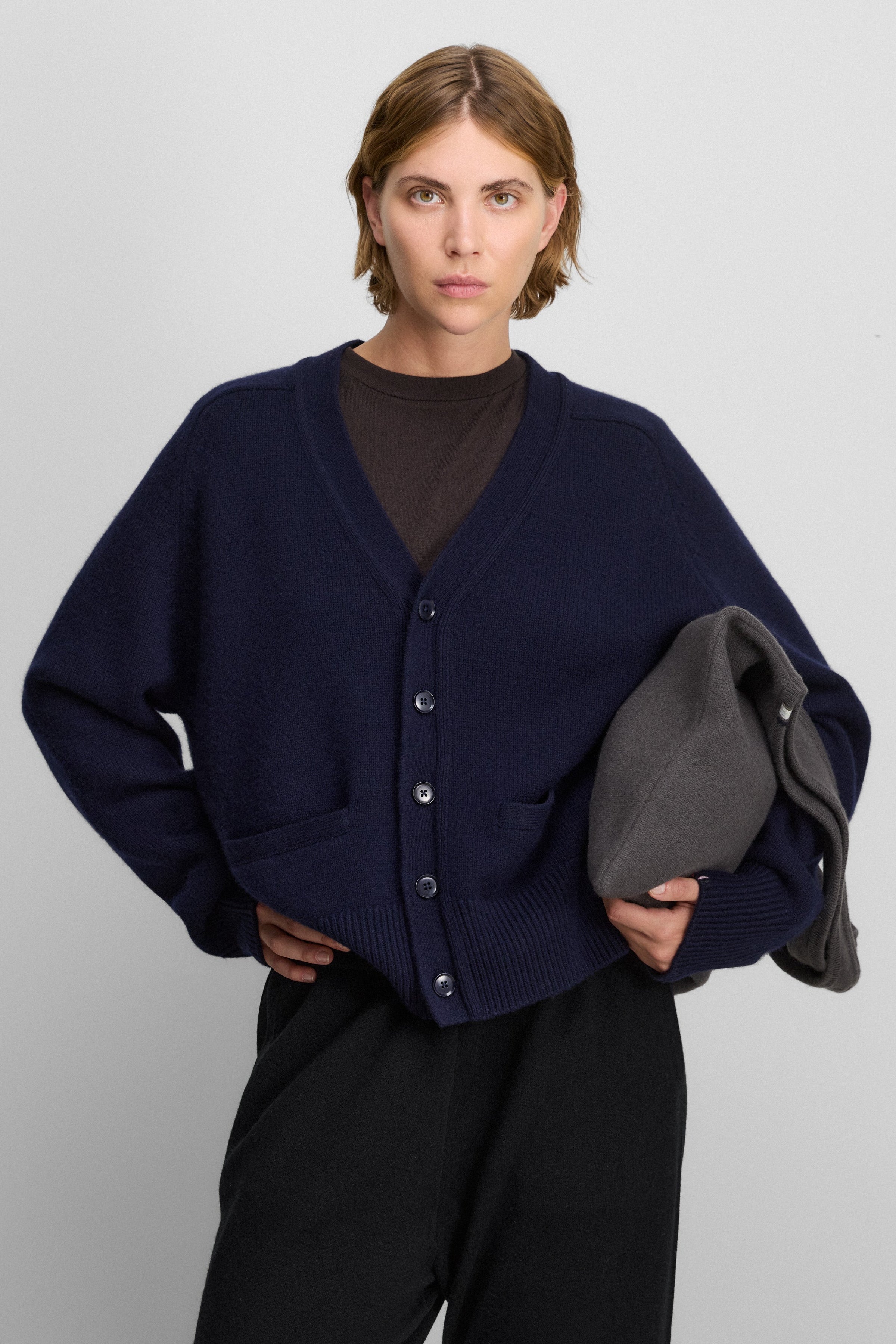 woman wearing a navy blue heavy-knit cashmere v-neck cardigan with five corozo buttons and ribbed trims.