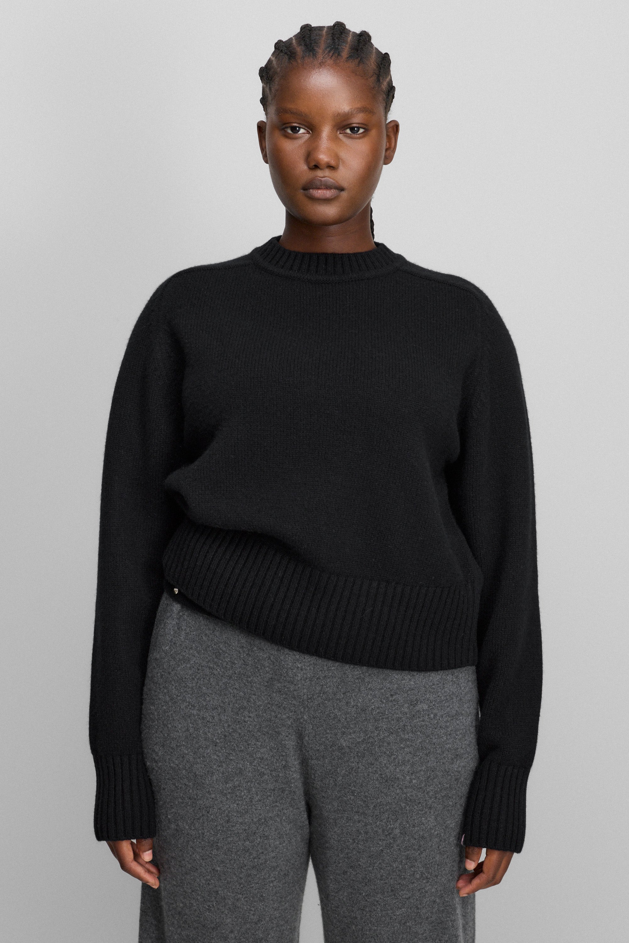 woman wearing a black heavy-knit cashmere crew-neck sweater with saddle shoulder and ribbed trims.