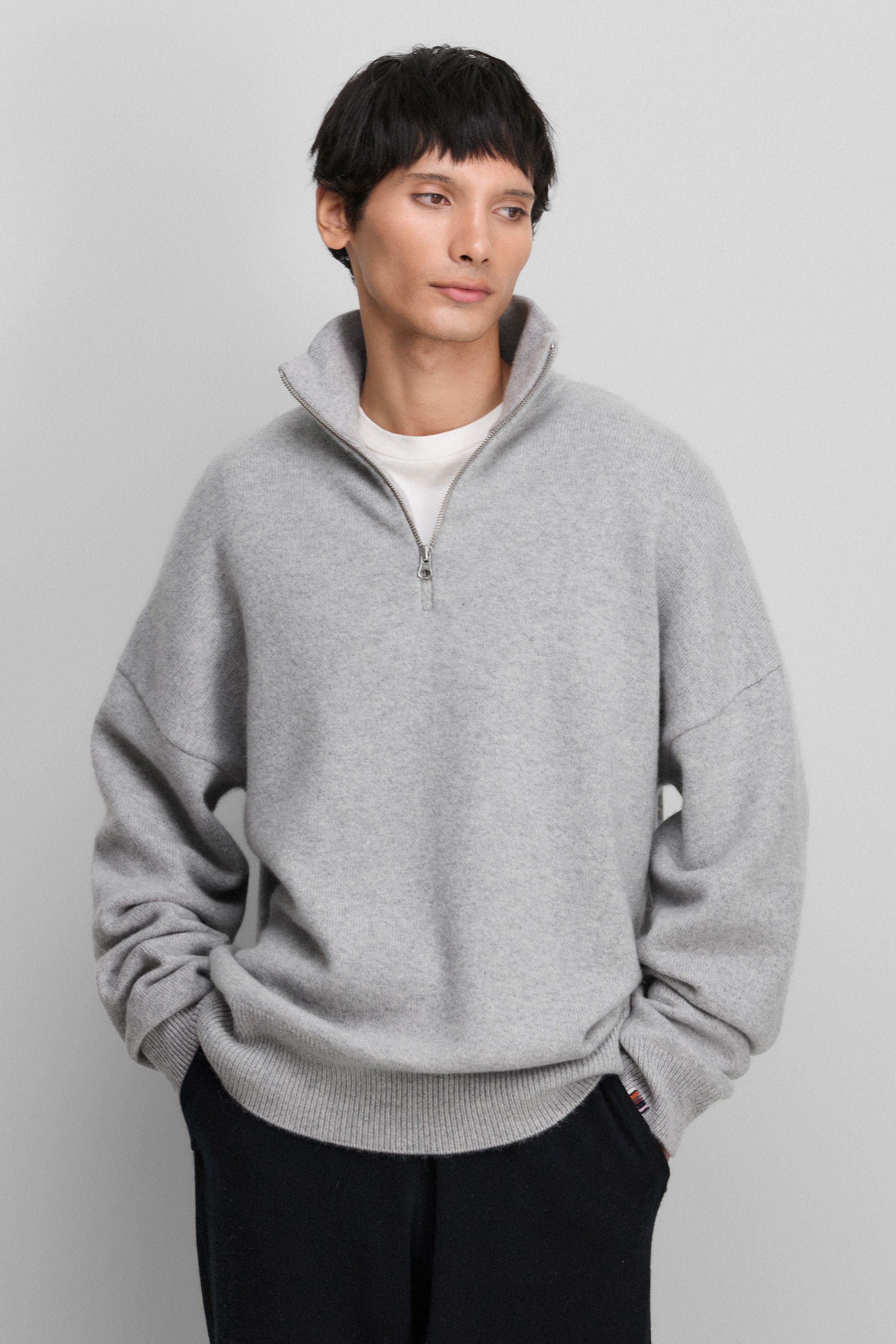 man wearing a light grey quarter-zip cashmere sweater with drop shoulder and ribbed hem and cuffs.