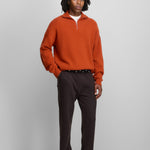 man wearing a dark orange quarter-zip cashmere sweater with drop shoulder and ribbed trims.