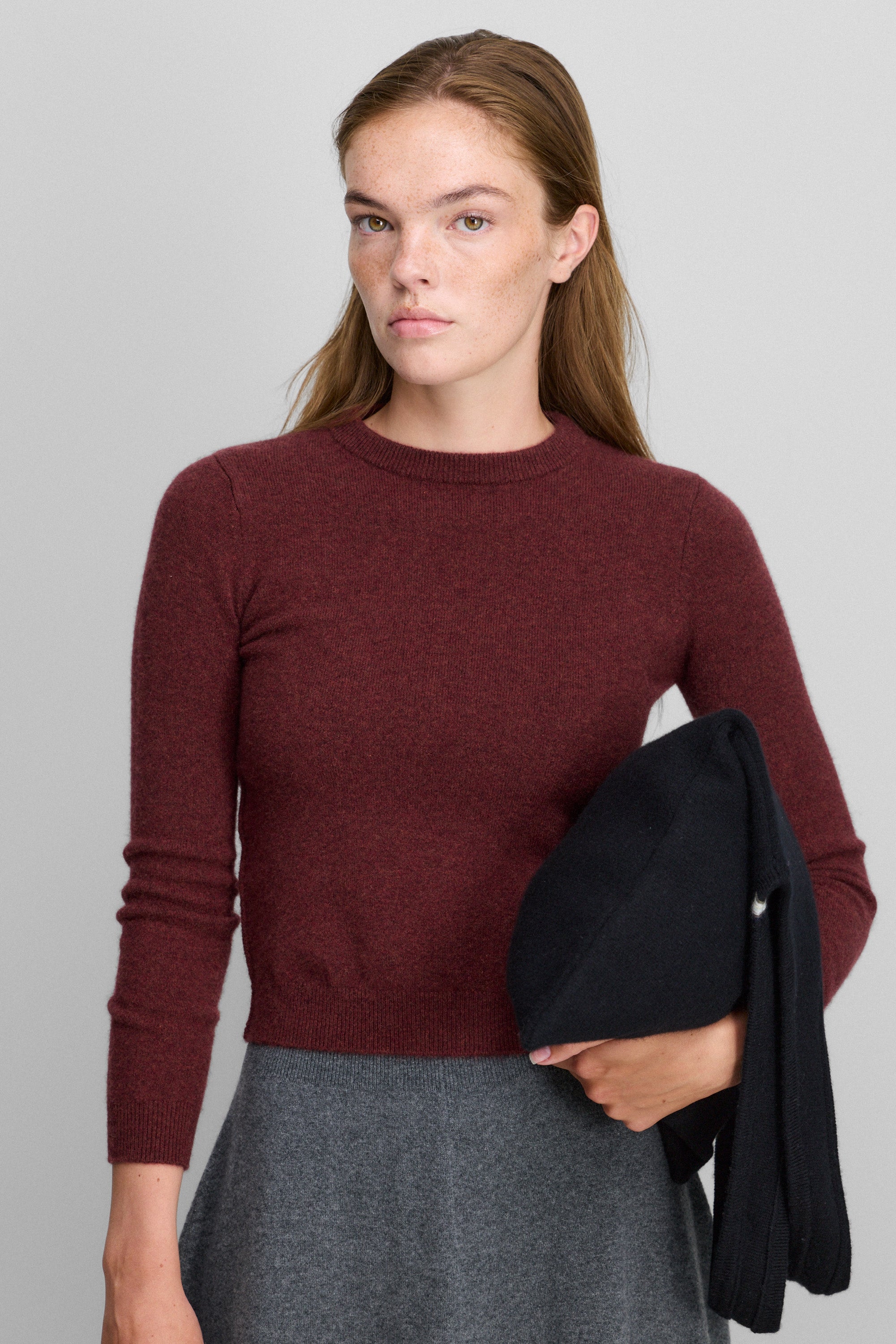woman wearing a burgundy slim-fit cashmere crewneck sweater with ribbed trims.