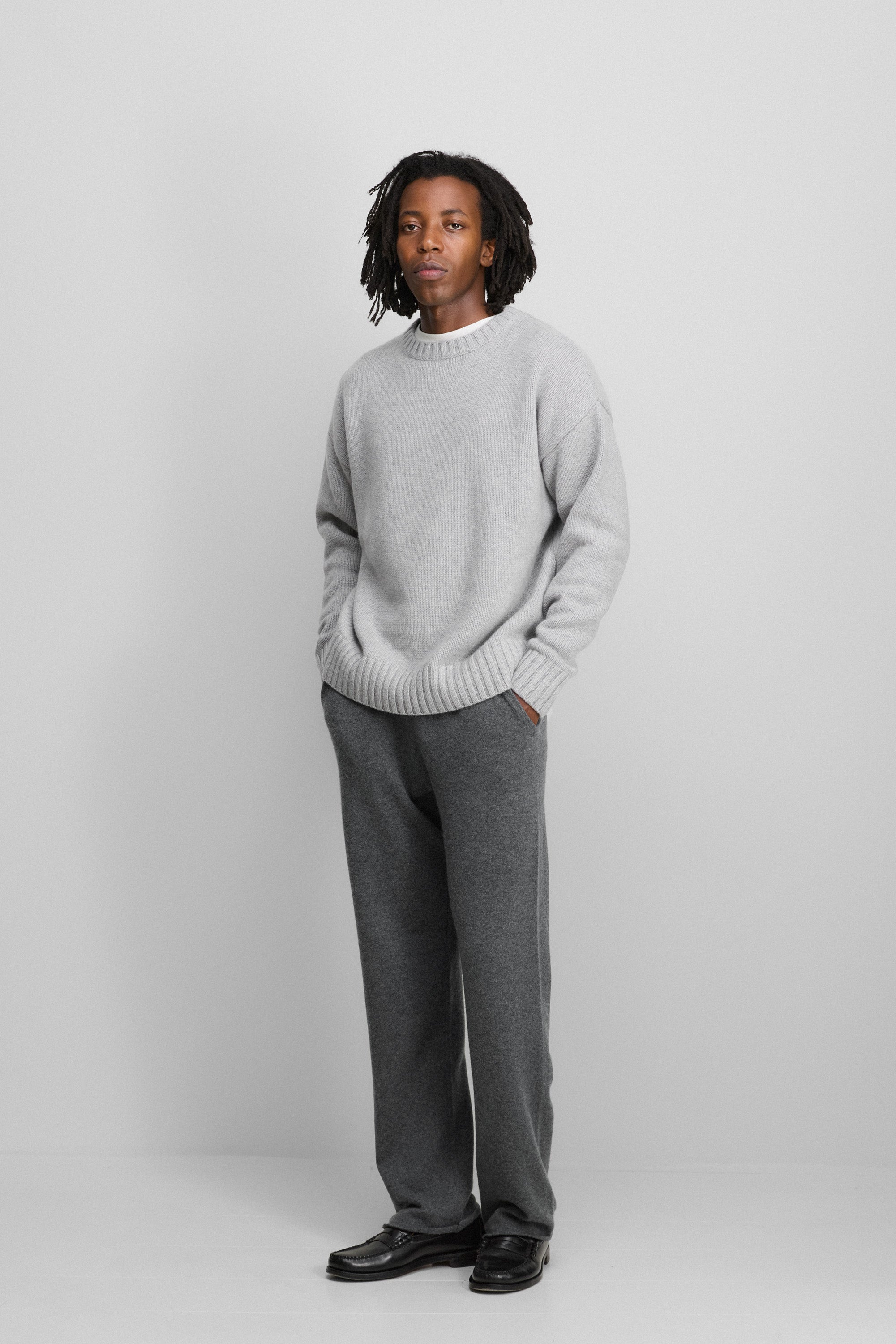 man wearing a grey relaxed-fit cashmere crew-neck sweater, styled with dark grey pants.