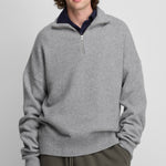 man wearing a grey quarter-zip cashmere sweater with drop shoulder and ribbed hem and cuffs.
