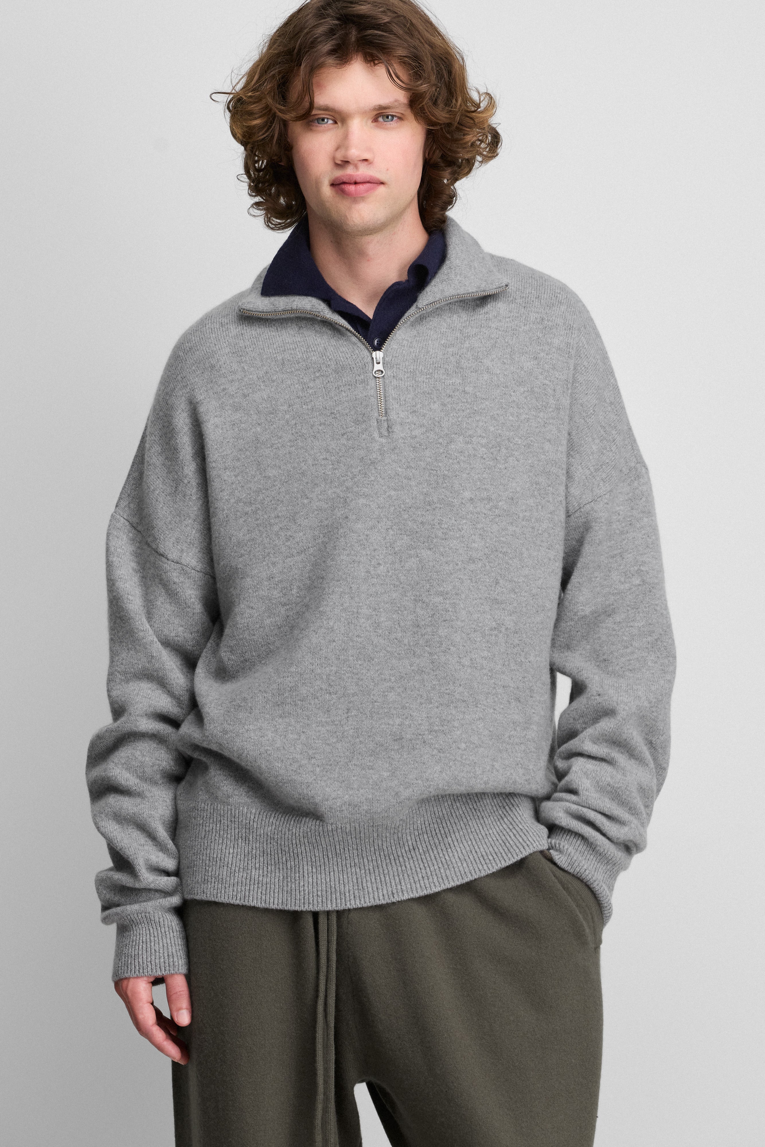 man wearing a grey quarter-zip cashmere sweater with drop shoulder and ribbed hem and cuffs.