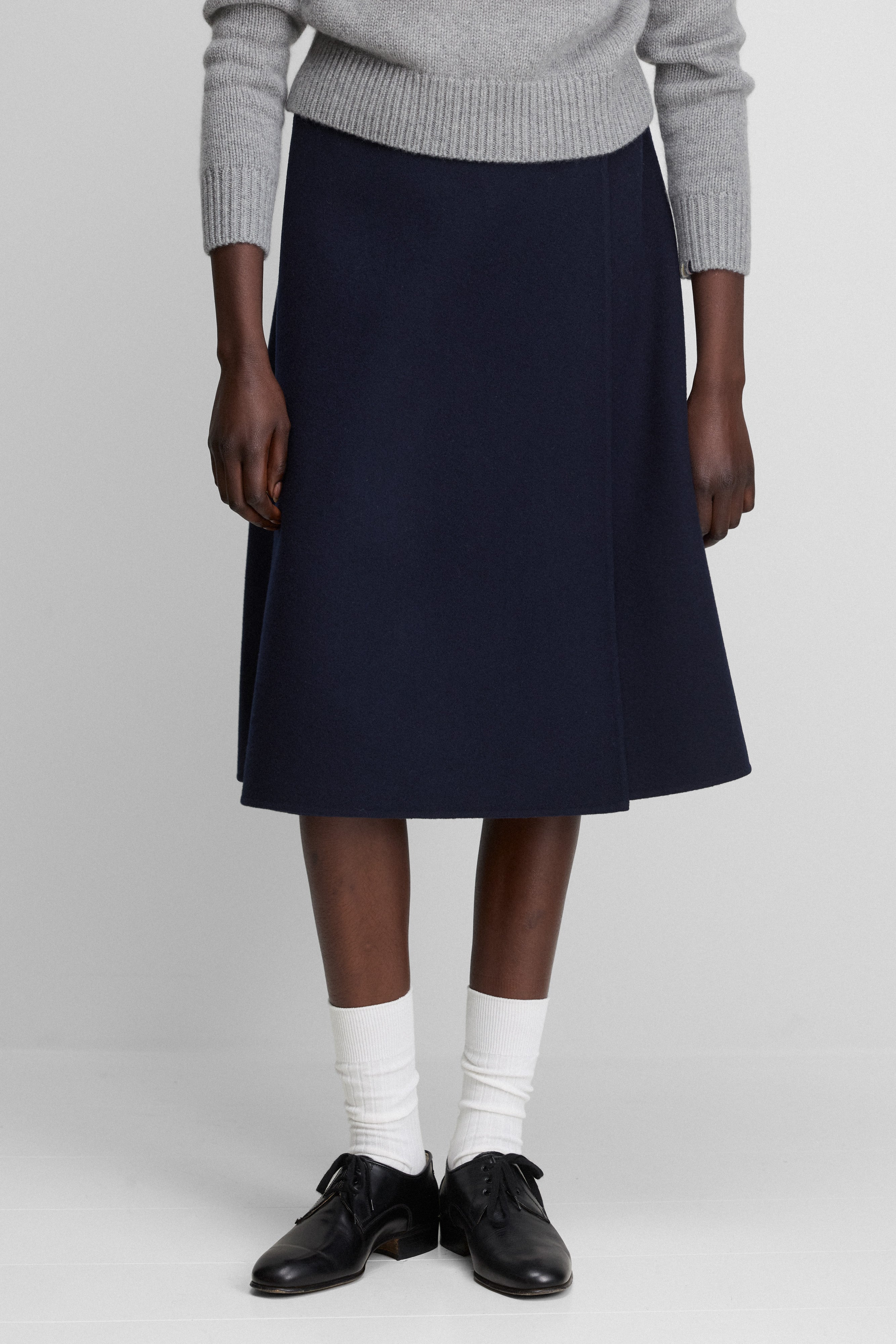 woman wearing a navy-blue double-faced wool-cashmere midi wrap skirt with an a-line silhouette.