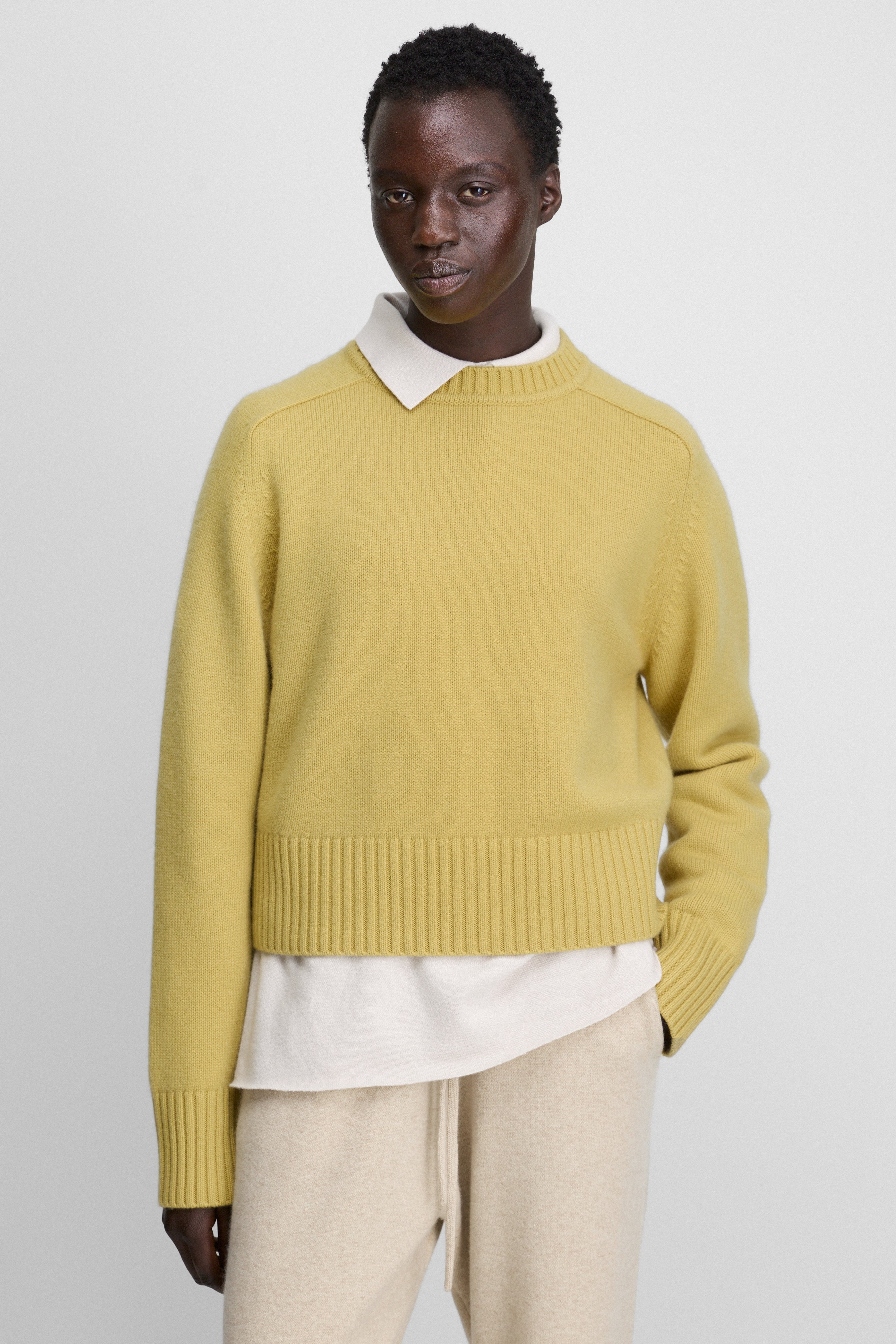 woman wearing a yellow heavy-knit cashmere crew-neck sweater with saddle shoulder and ribbed trims.