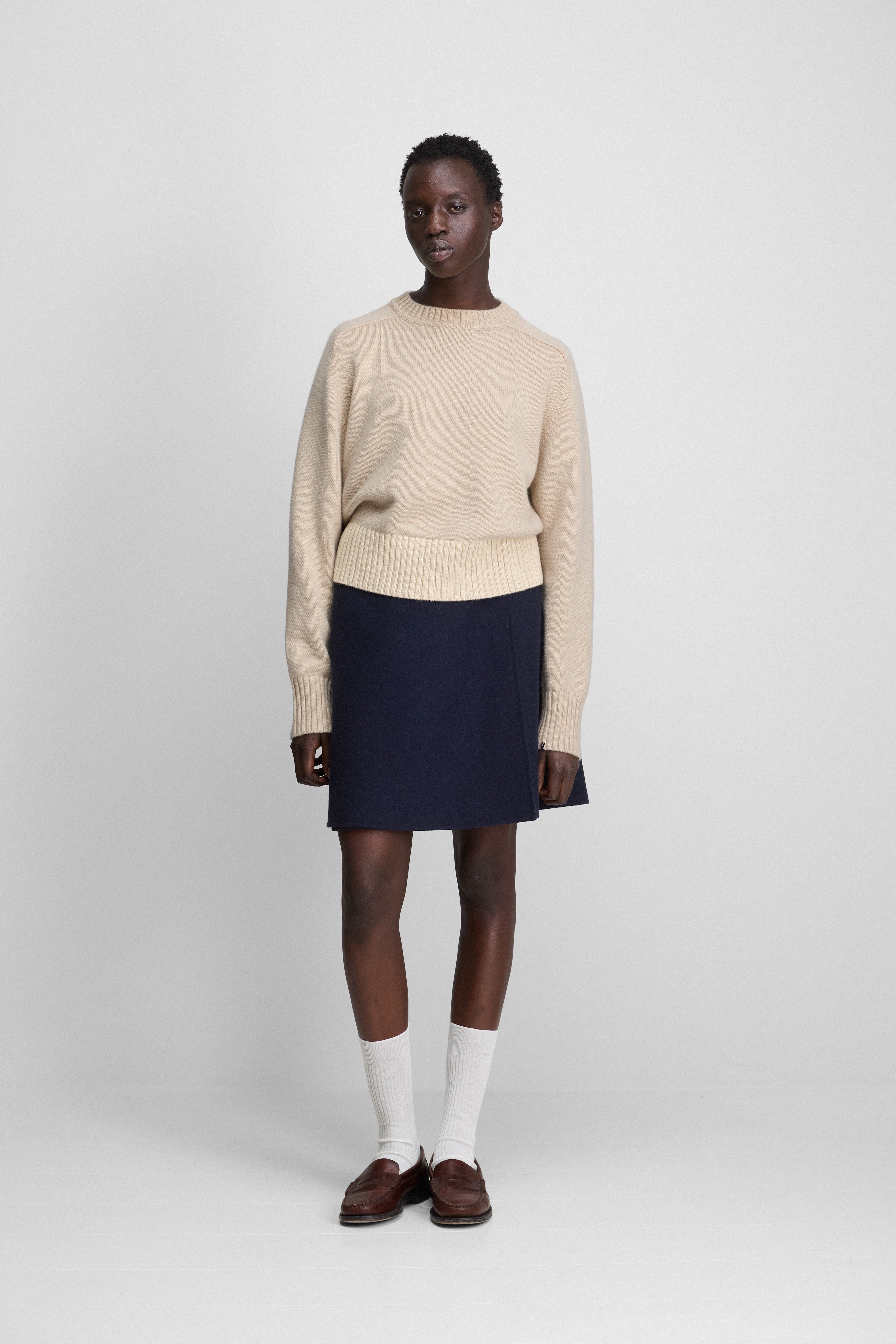 woman wearing a short black double-faced wool wrap skirt with an a-line silhouette, styled with a sweater.