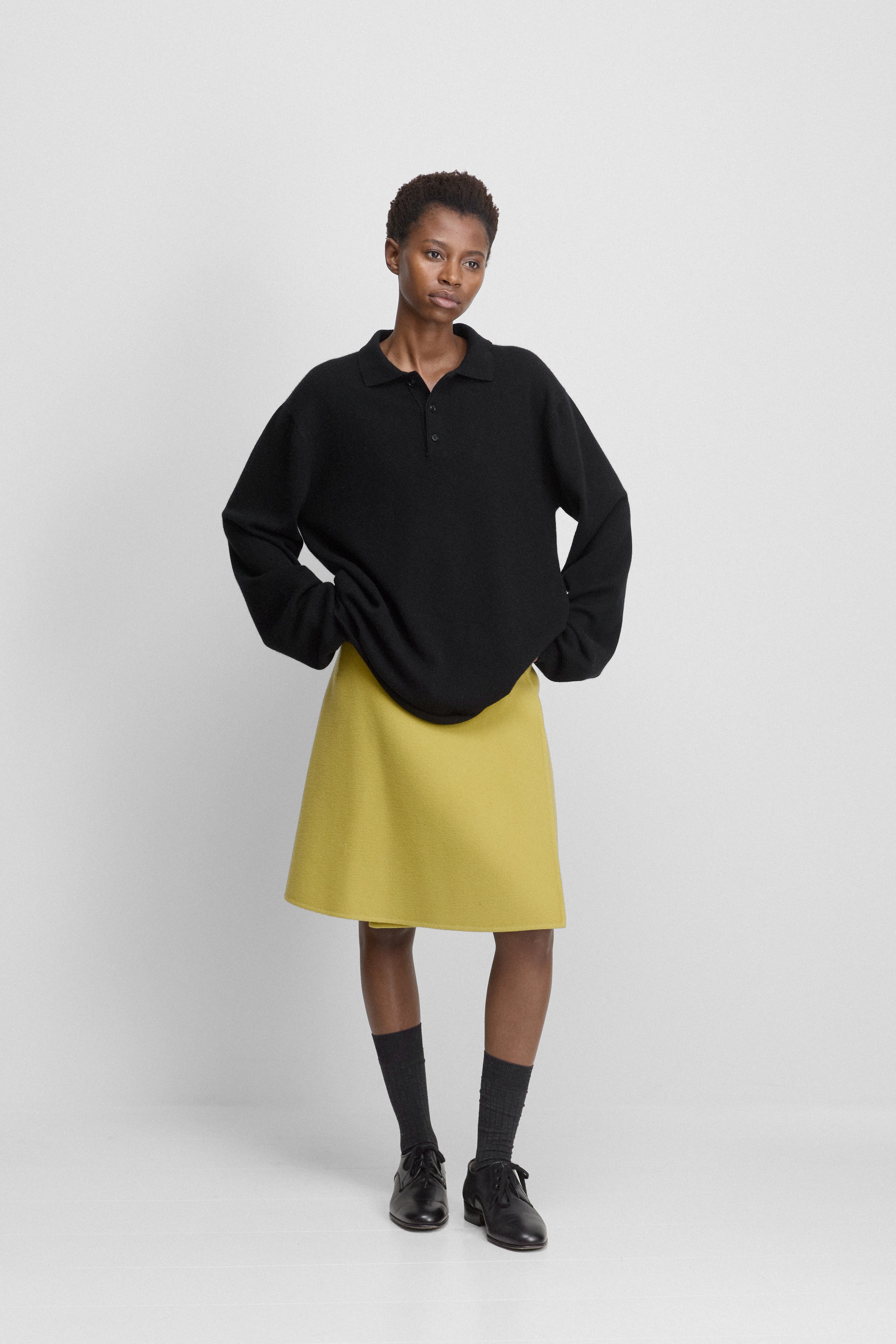 woman wearing a short yellow double-faced wool wrap skirt with an a-line silhouette, styled with a sweater.